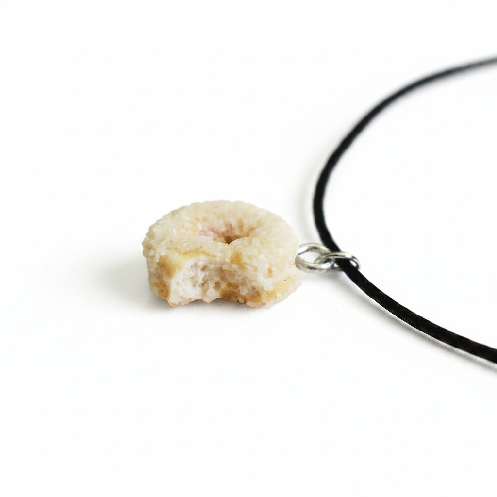 Donut-shaped pendant on a black cord against a light background