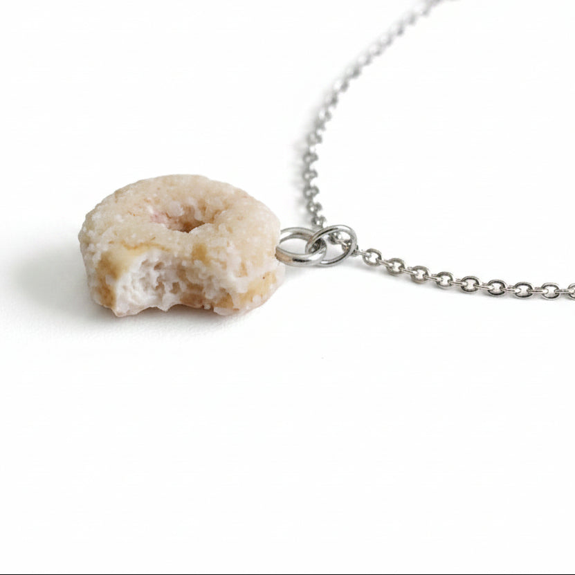 Donut-shaped pendant on a silver plated cable chain against a light background