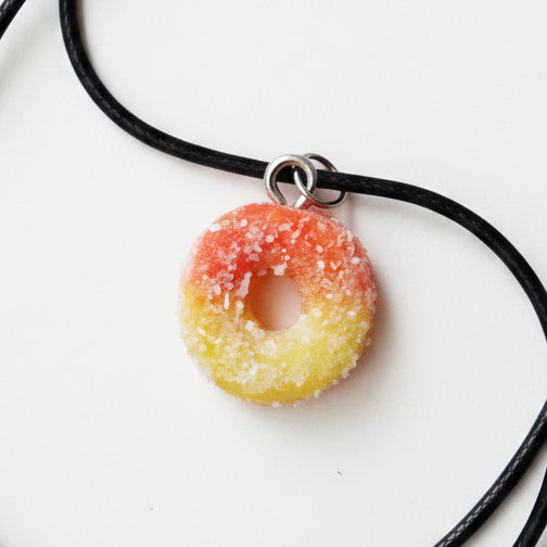 Necklace with a colorful gummy charm on a light yellow background