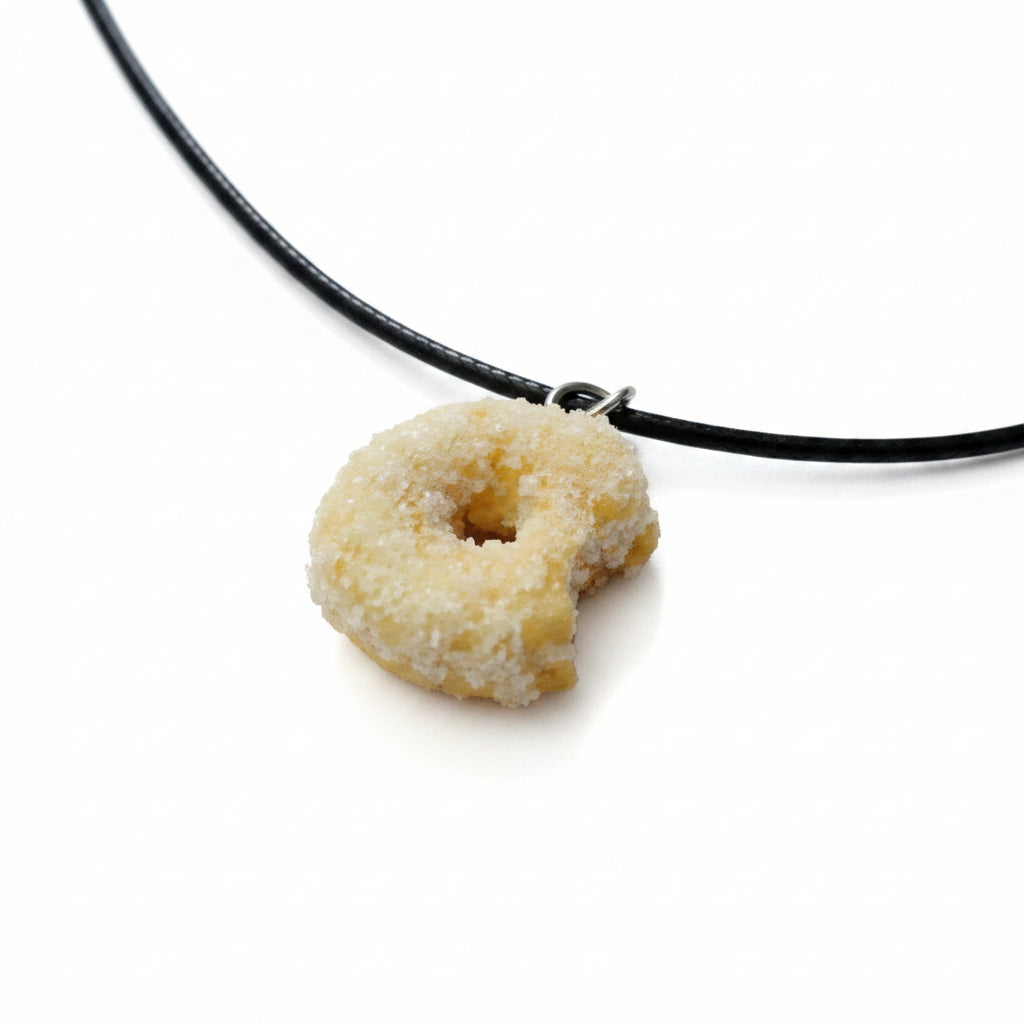Donut-shaped pendant on a black cord against a yellow background