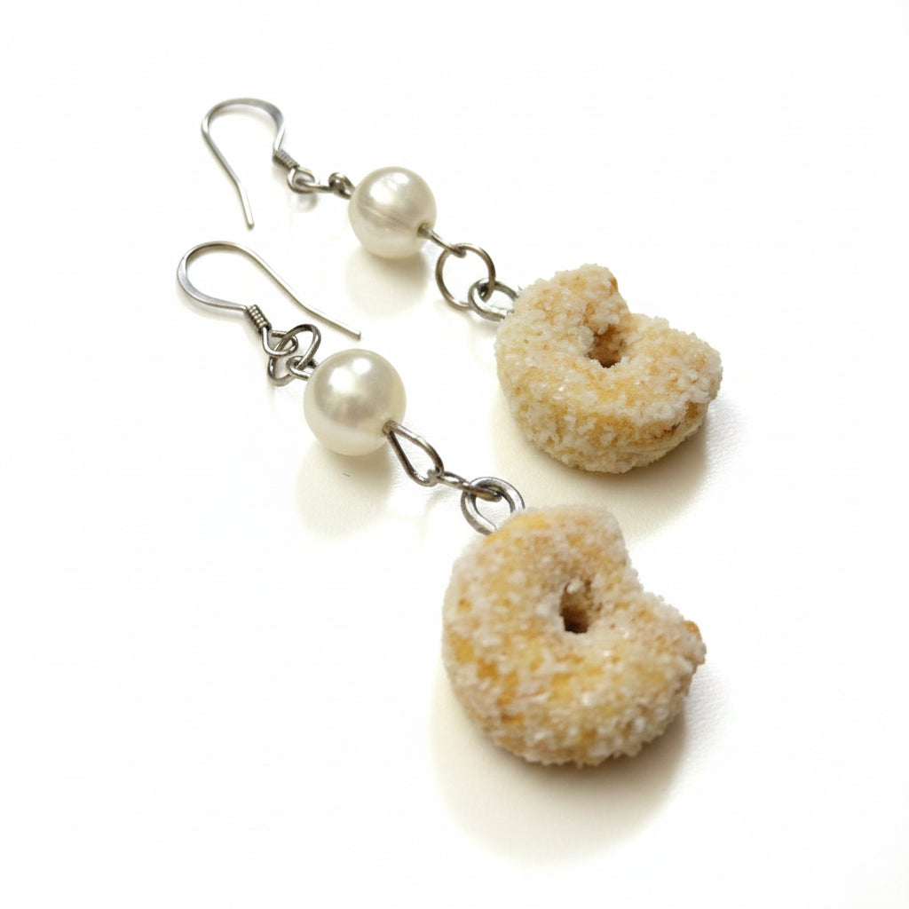 Donut-shaped earrings with pearl-like beads on a white background