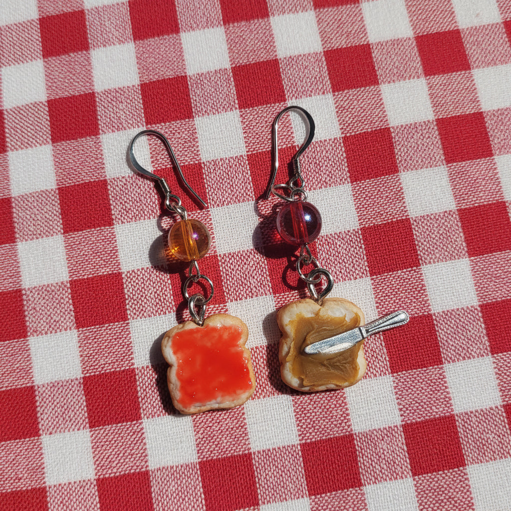 Earrings with bread and knife charms on a plaid background