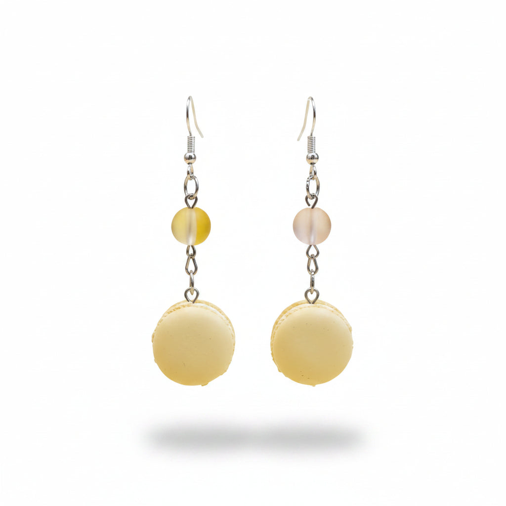 Pair of earrings with yellow macaron-shaped beads and small ribbons on a light gray background