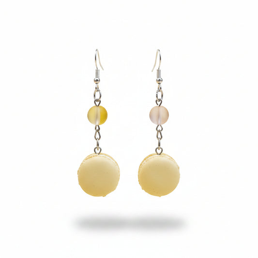 Pair of earrings with yellow macaron-shaped beads and small ribbons on a light gray background