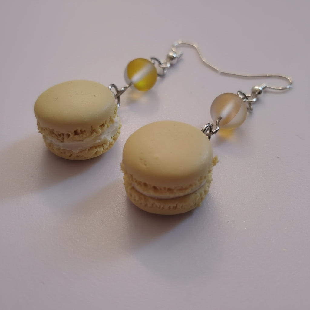 Macaron-shaped earrings with yellow beads on a white surface
