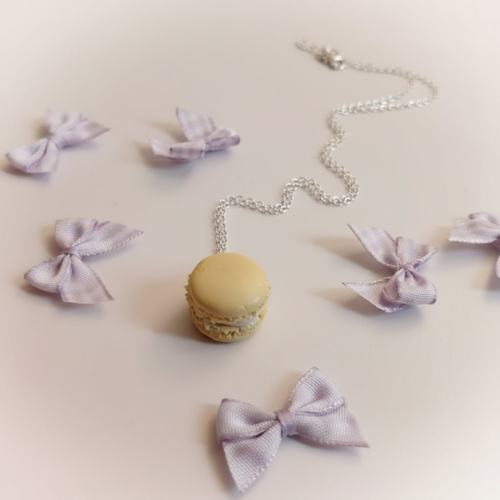 Macaron-shaped pendant with a chain and purple bow decorations on a light surface