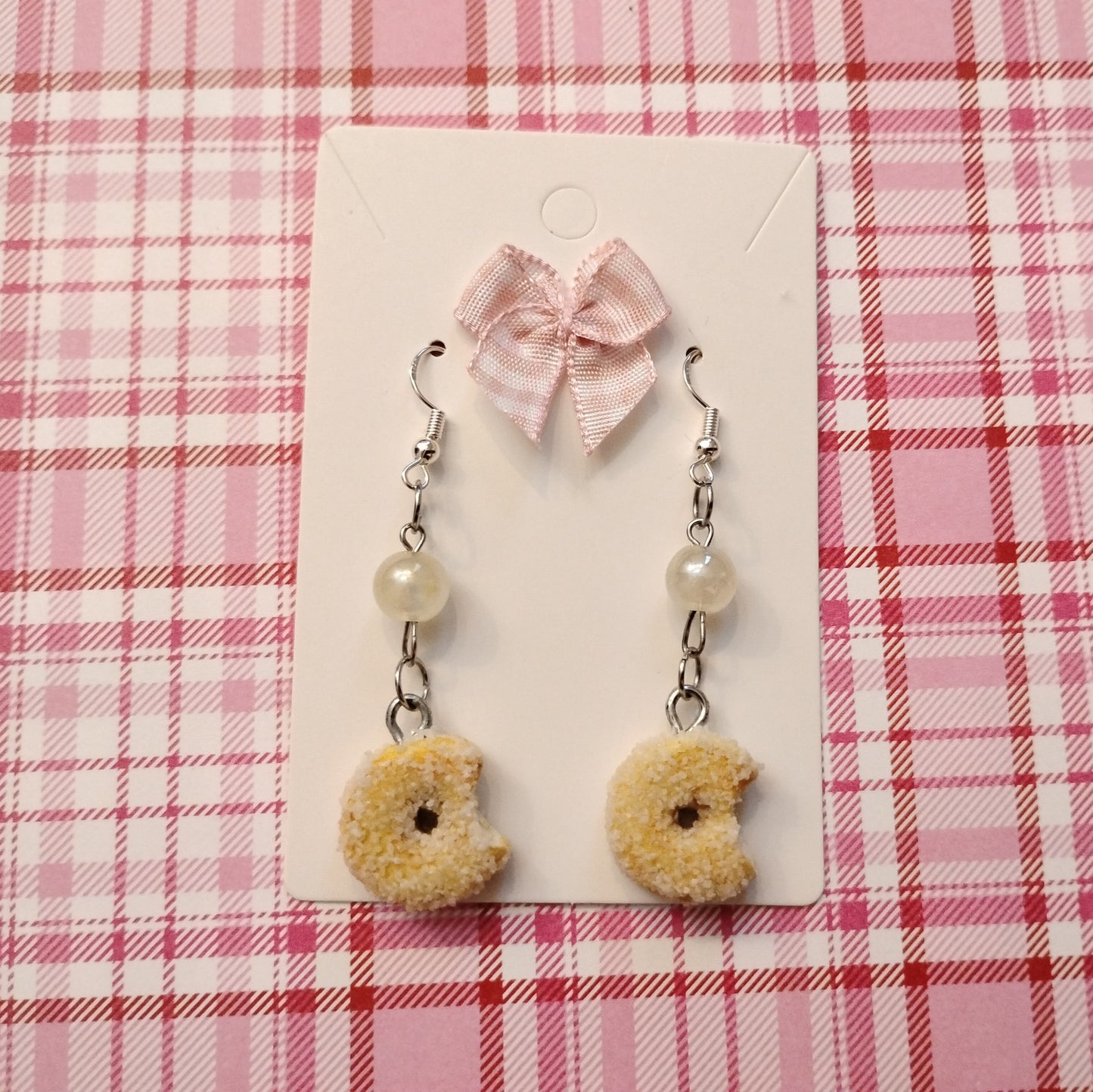 Donut-shaped earrings with pearls on a pink plaid background