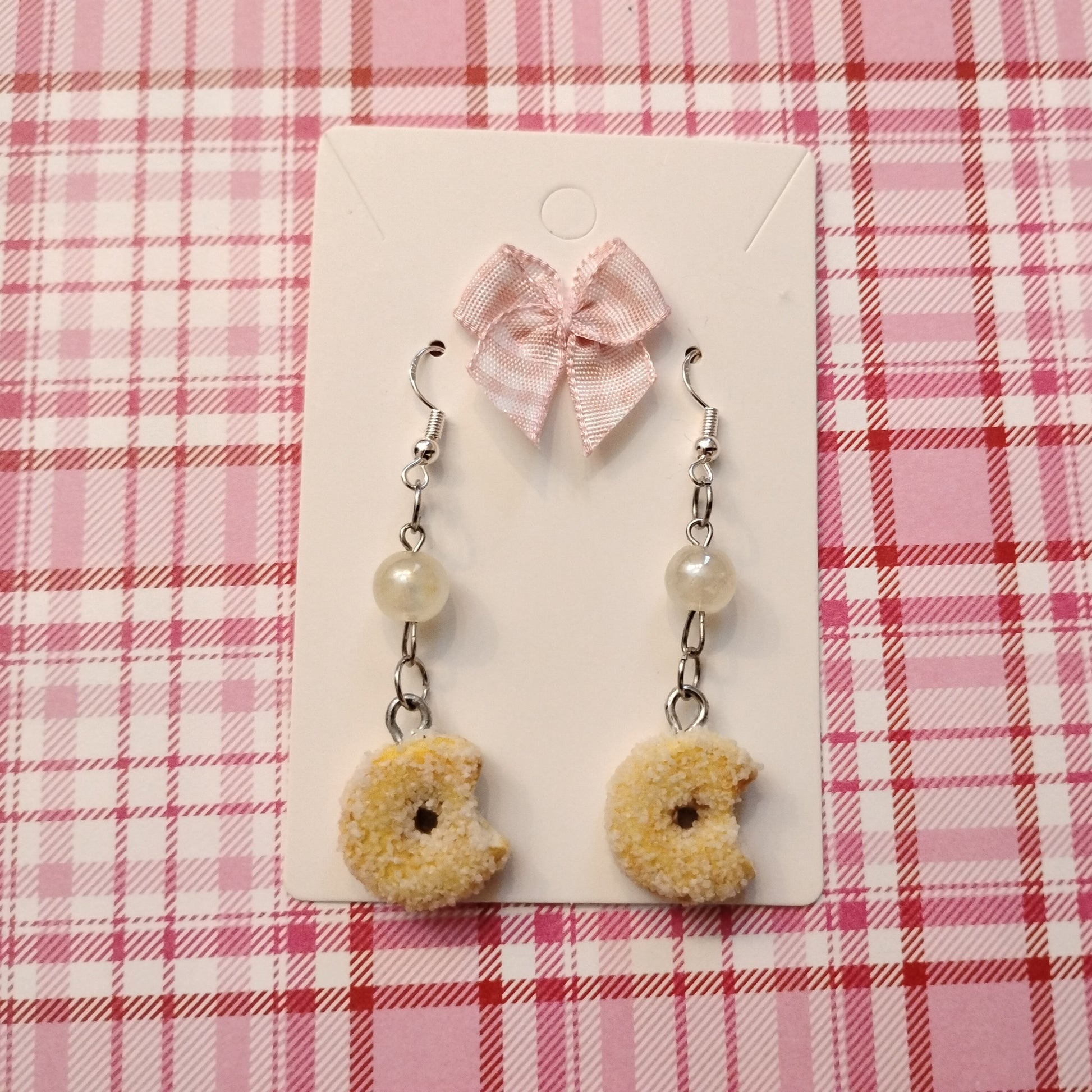 Donut-shaped earrings with pearls on a pink plaid background