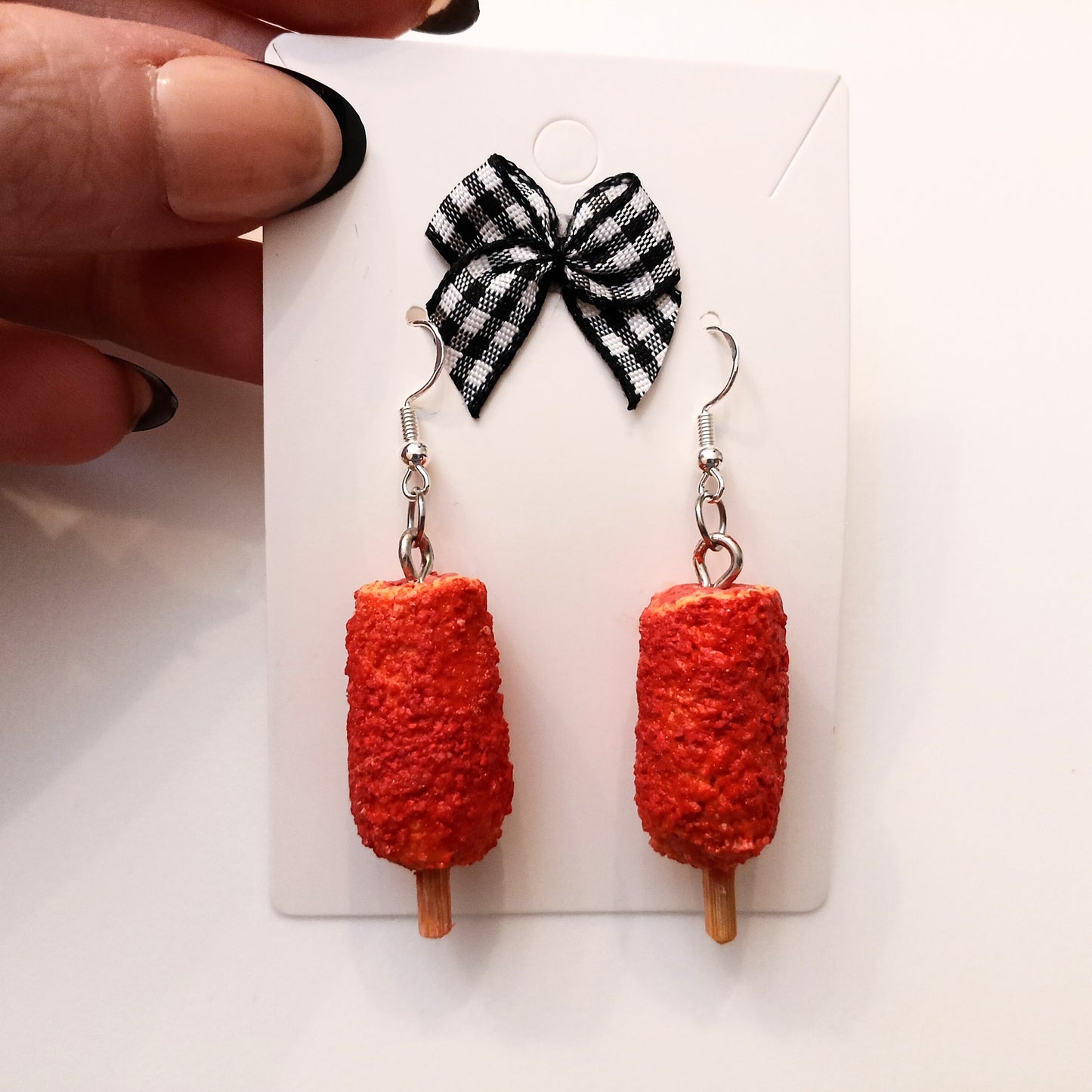 korean corn dog earrings with a black and white checkered bow on a white card.