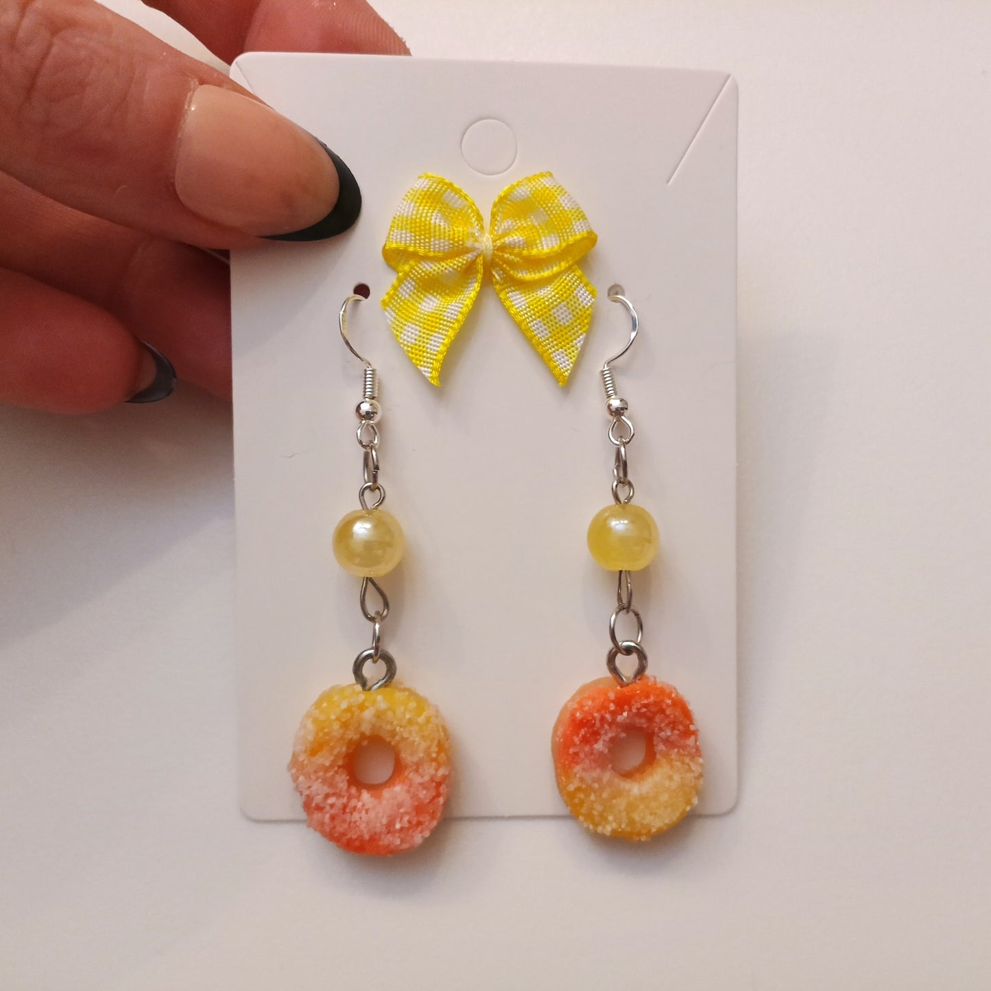 peach rings earrings with a yellow bow on a white card.