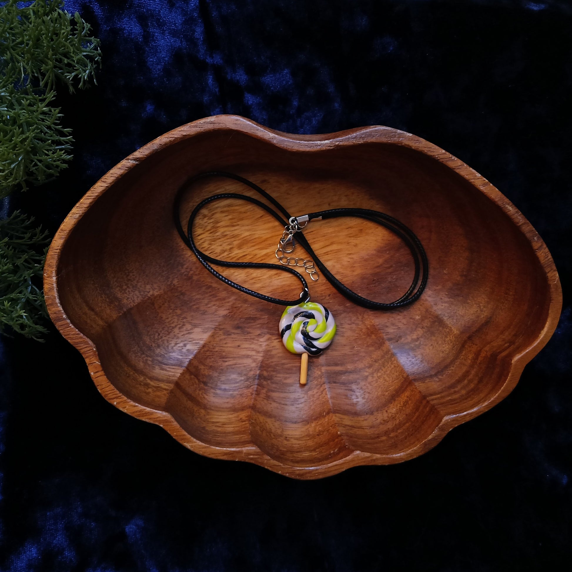 Necklace with a colorful pendant on a wooden dish against a dark background