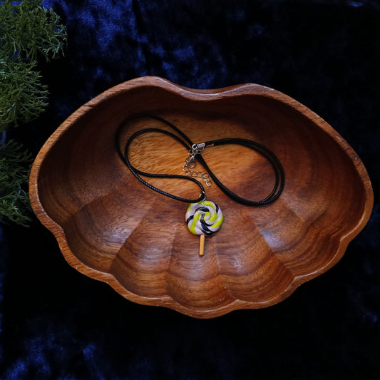 Necklace with a colorful pendant on a wooden dish against a dark background