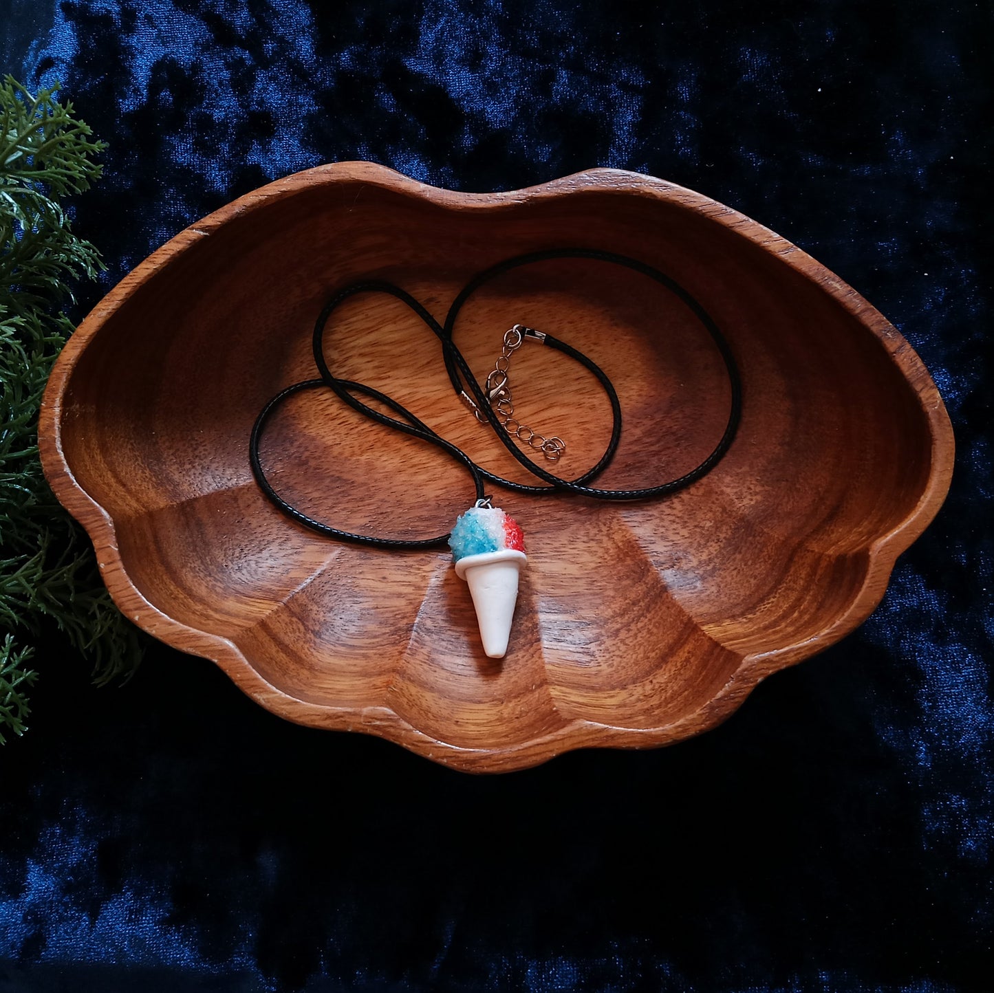 Necklace with a colorful pendant in a wooden bowl on a dark background