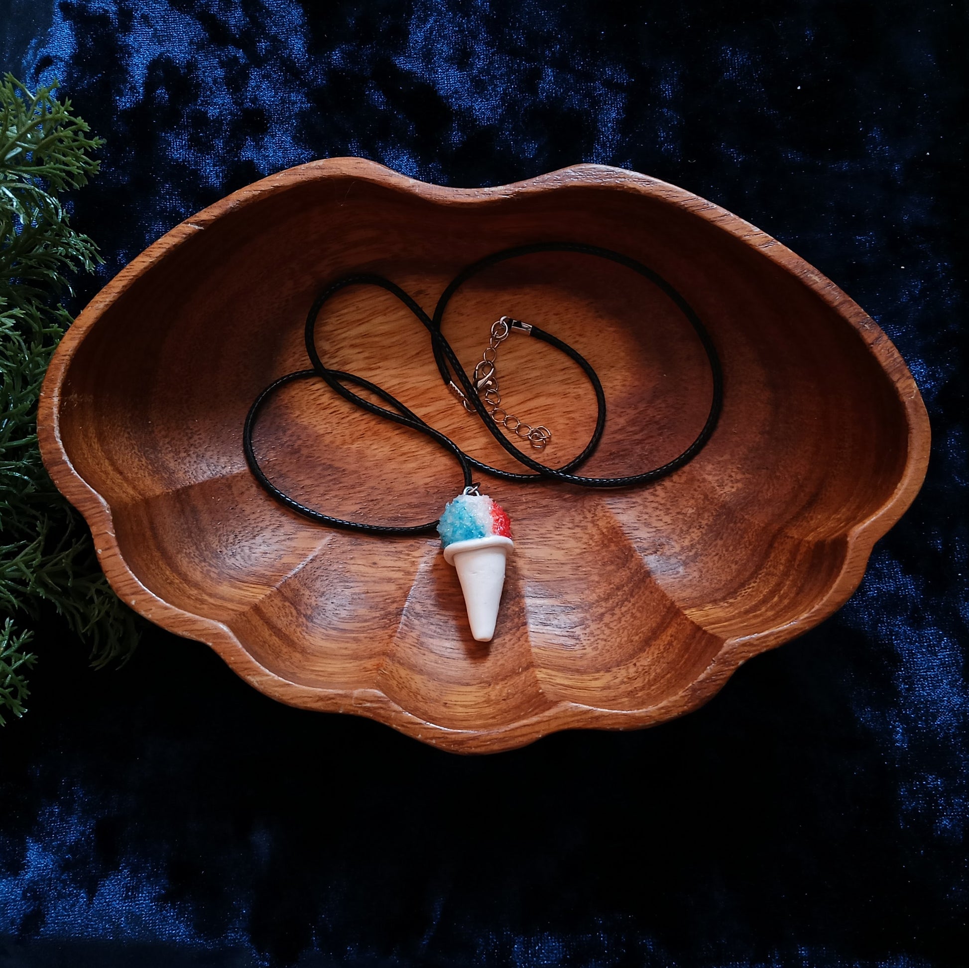 Necklace with a colorful pendant in a wooden bowl on a dark background