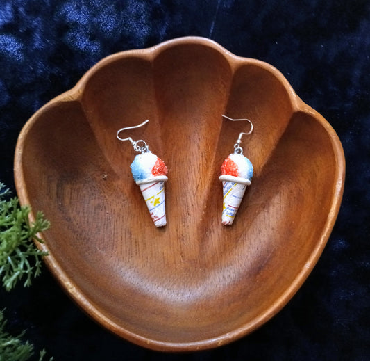 snow cone earrings on a wooden dish with a dark background