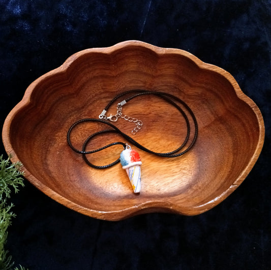 Necklace with a pendant in a wooden bowl on a dark background