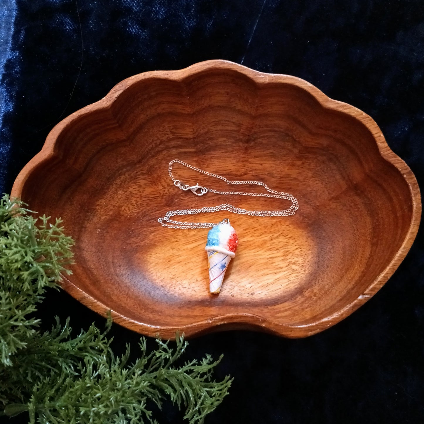 Necklace with a colorful pendant on a wooden dish against a dark background