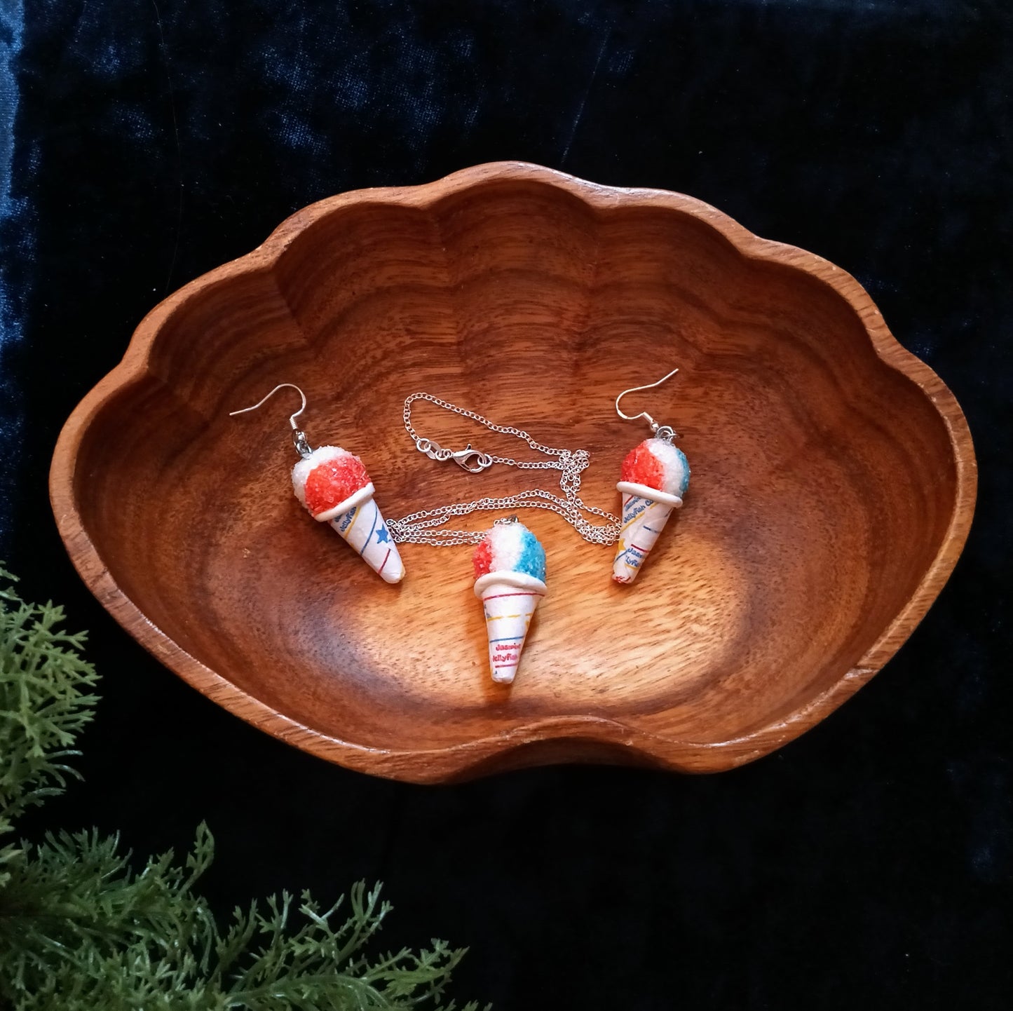Wooden bowl with snow cone-shaped earrings and a necklace on a dark background