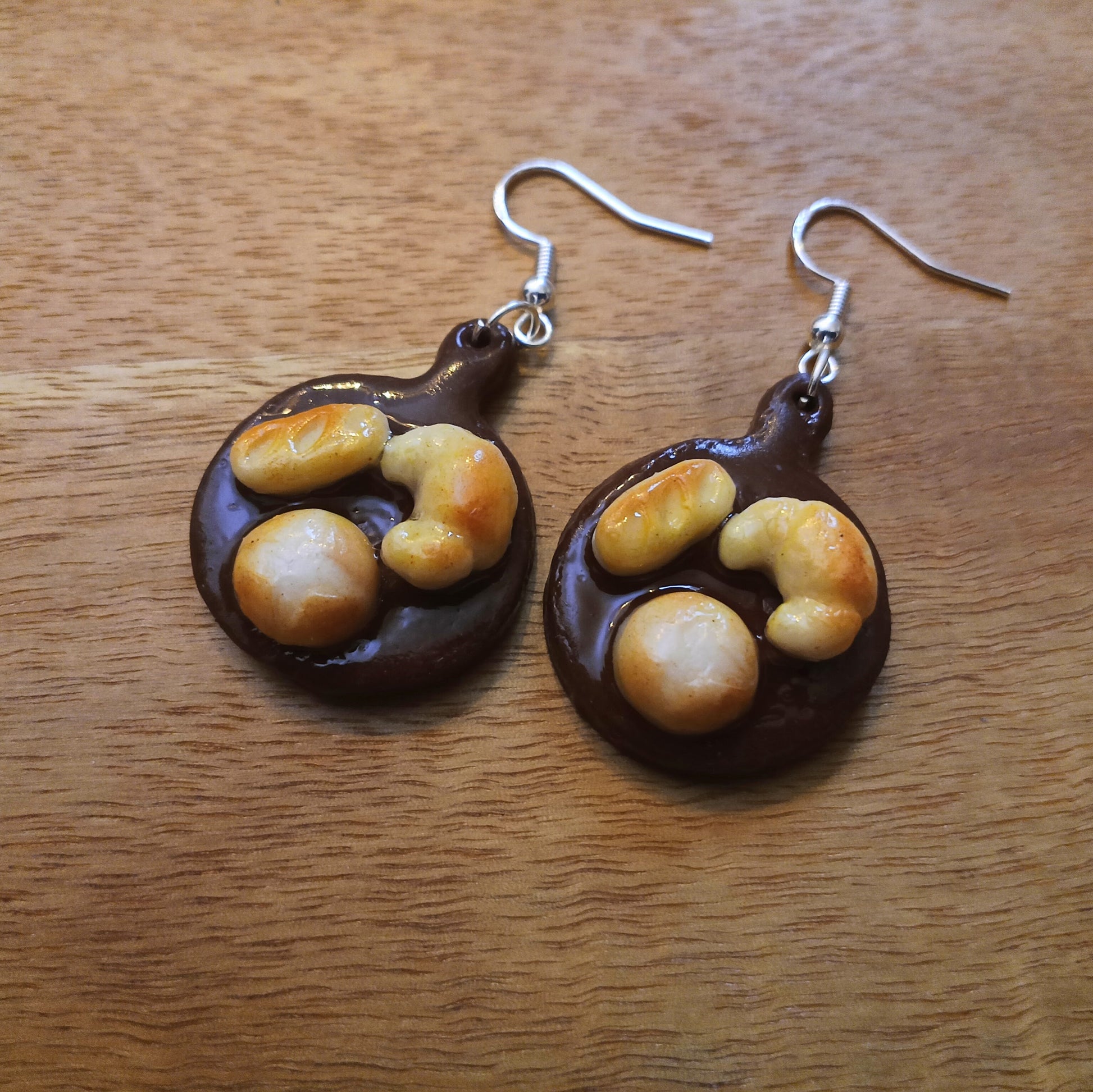 Pair of earrings with a design resembling cashews on a wooden surface