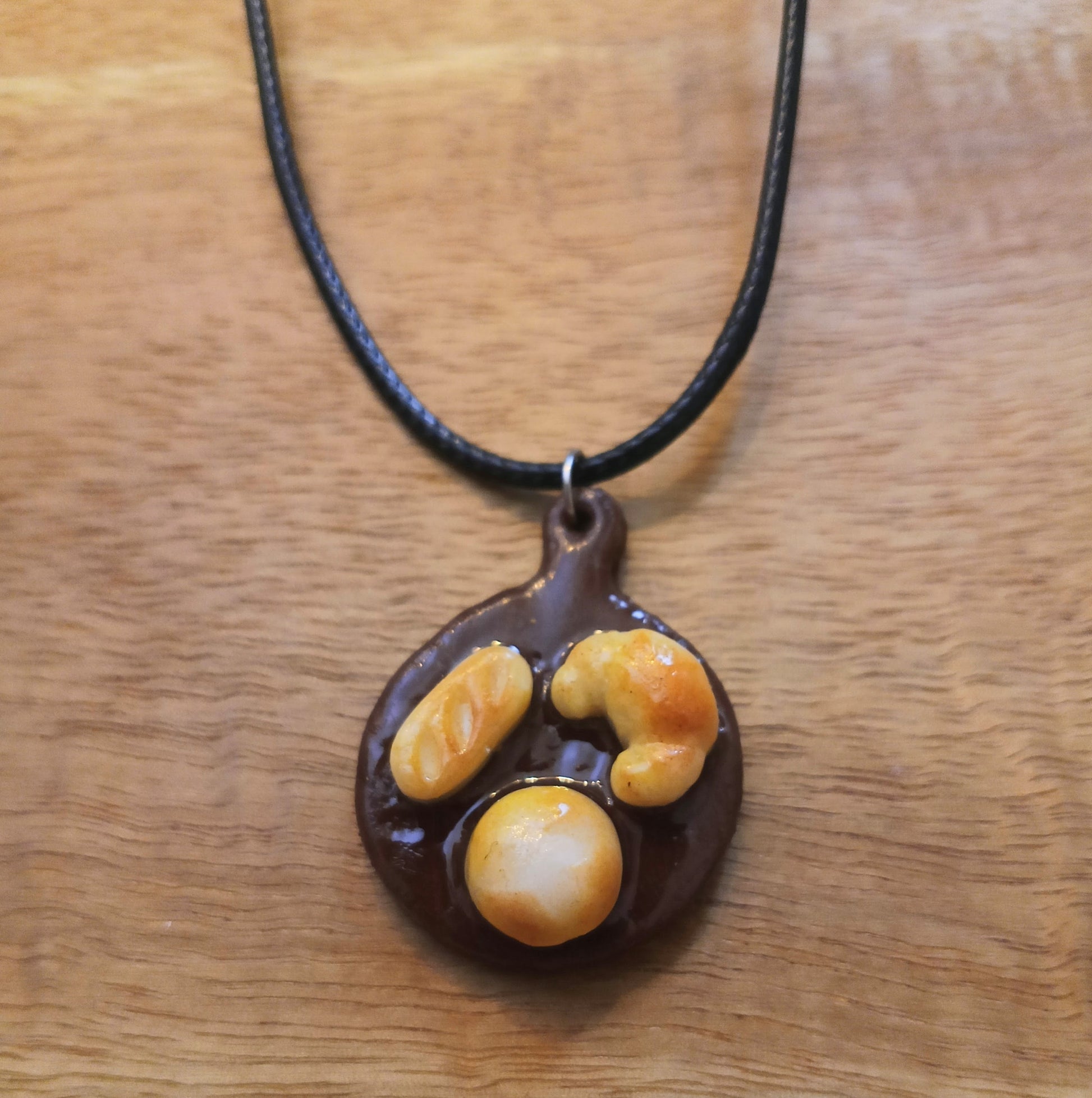 Necklace with a pendant shaped like a paw print on a wooden surface