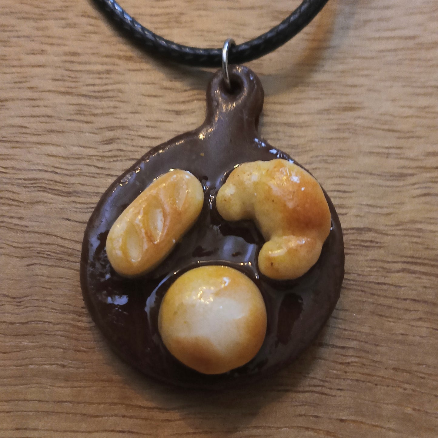 Chocolate pendant with three round, orange-brown stones on a wooden surface