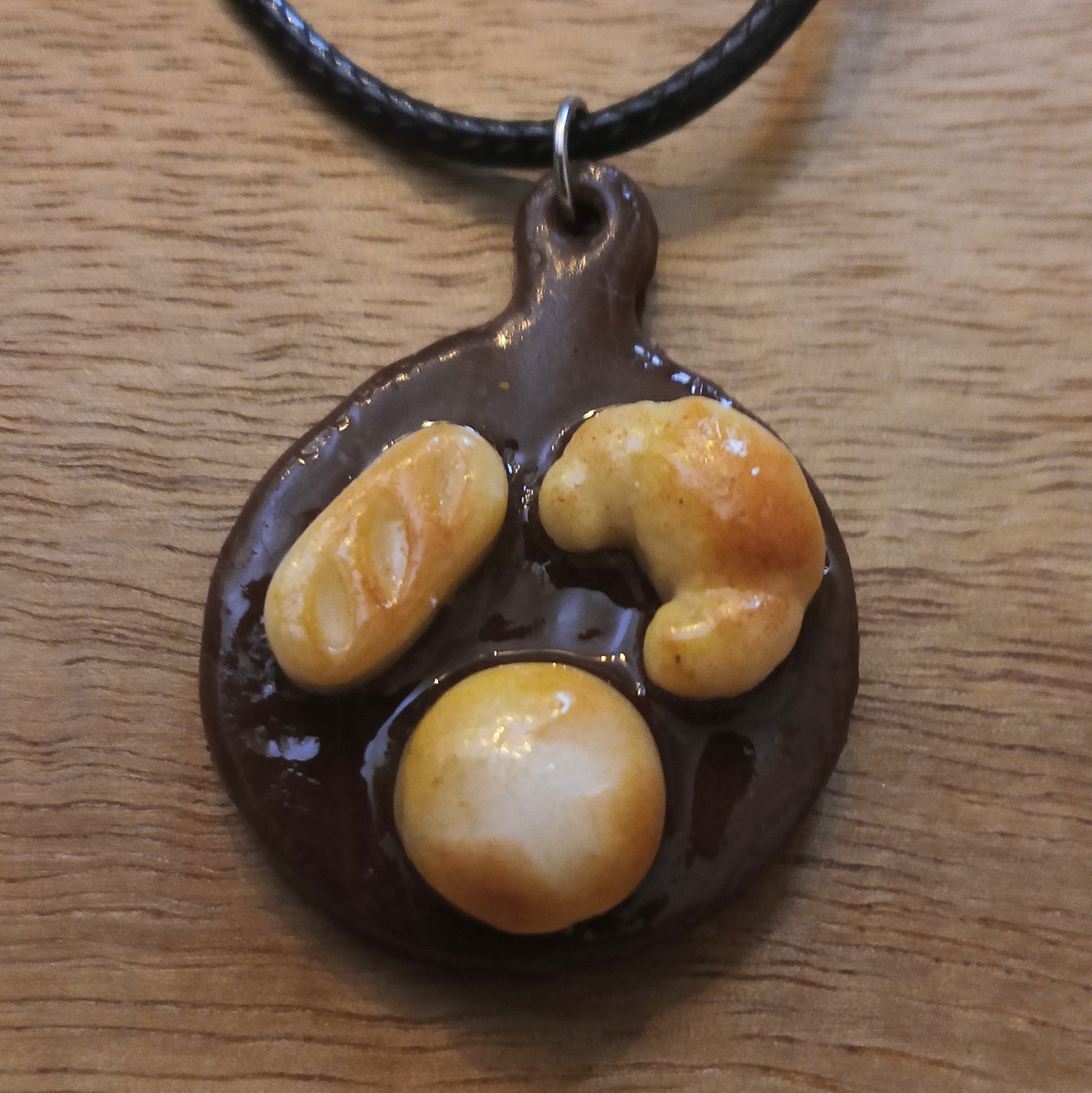 Chocolate pendant with three round, orange-brown stones on a wooden surface