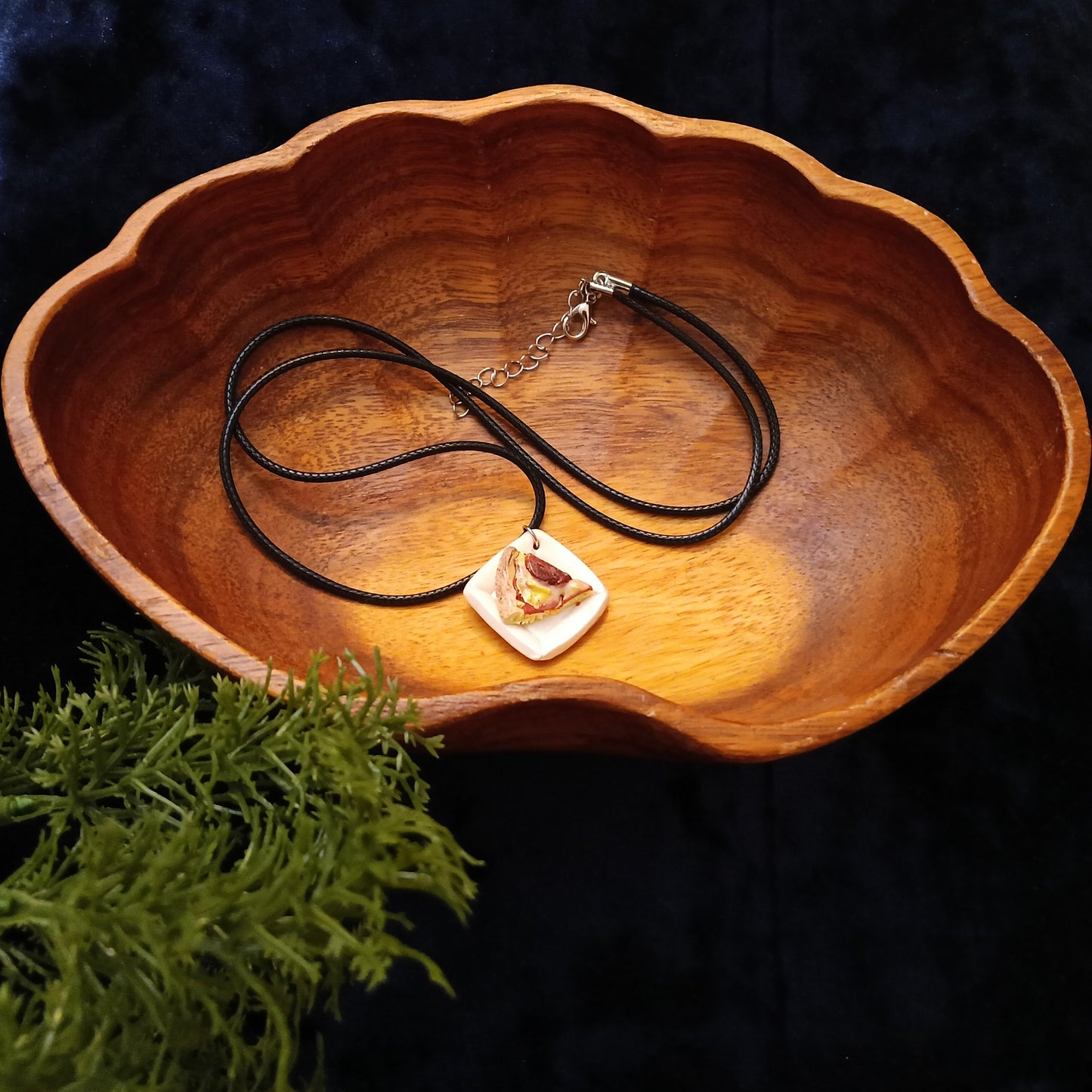 Necklace with a pendant in a wooden bowl on a dark background