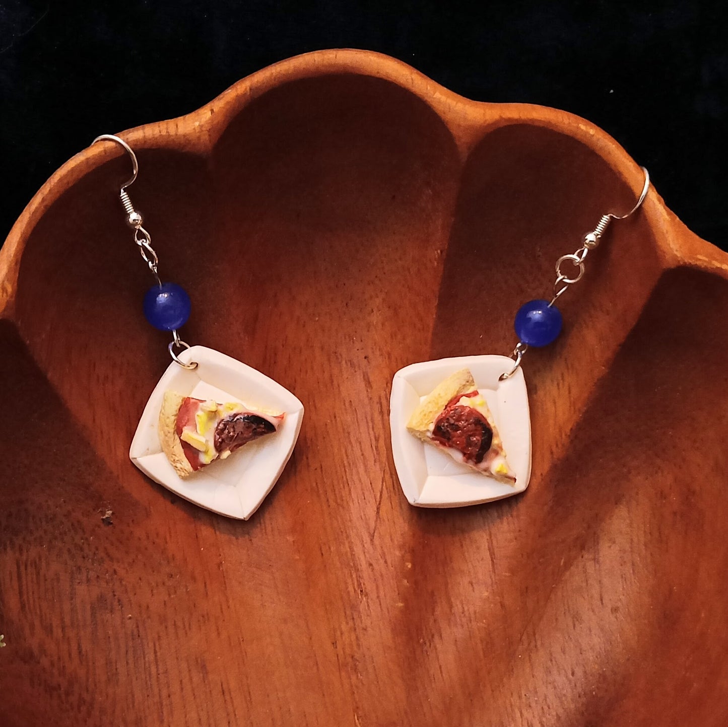 Pair of pizza-shaped earrings on a wooden surface