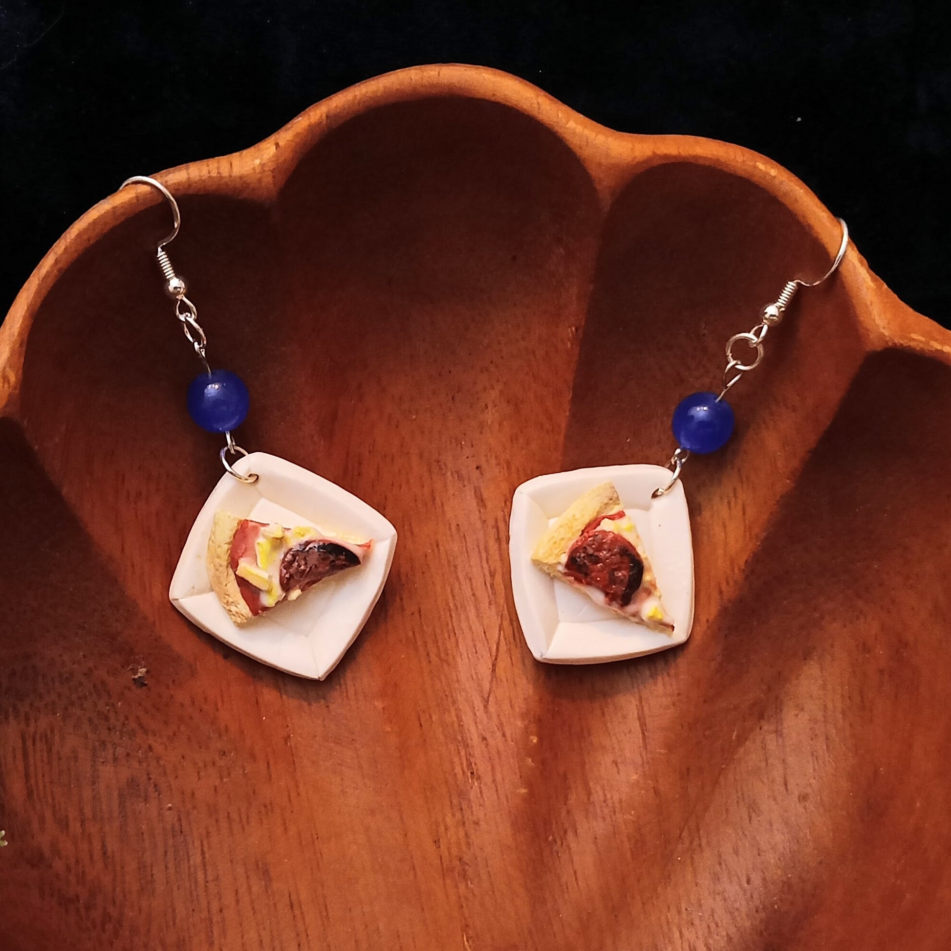 Pair of pizza-shaped earrings on a wooden surface