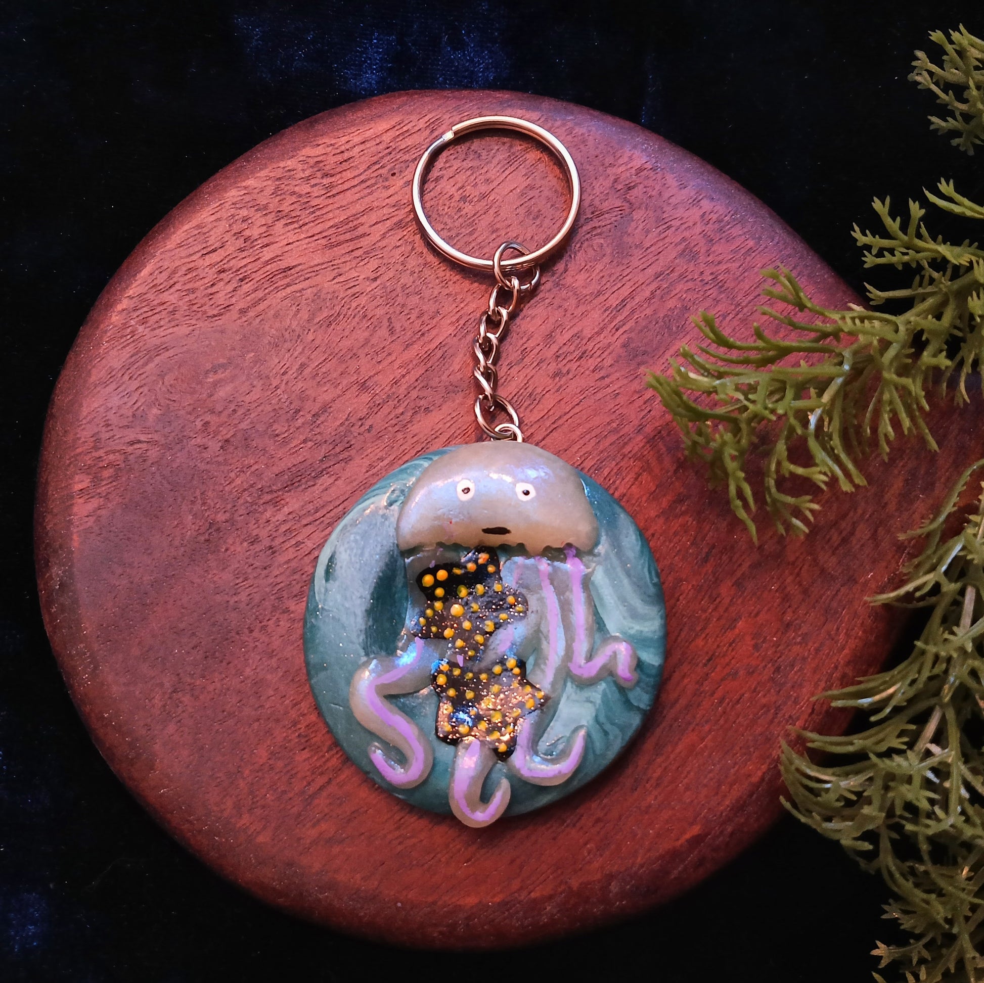 Keychain with jellyfish design on a wooden surface with greenery