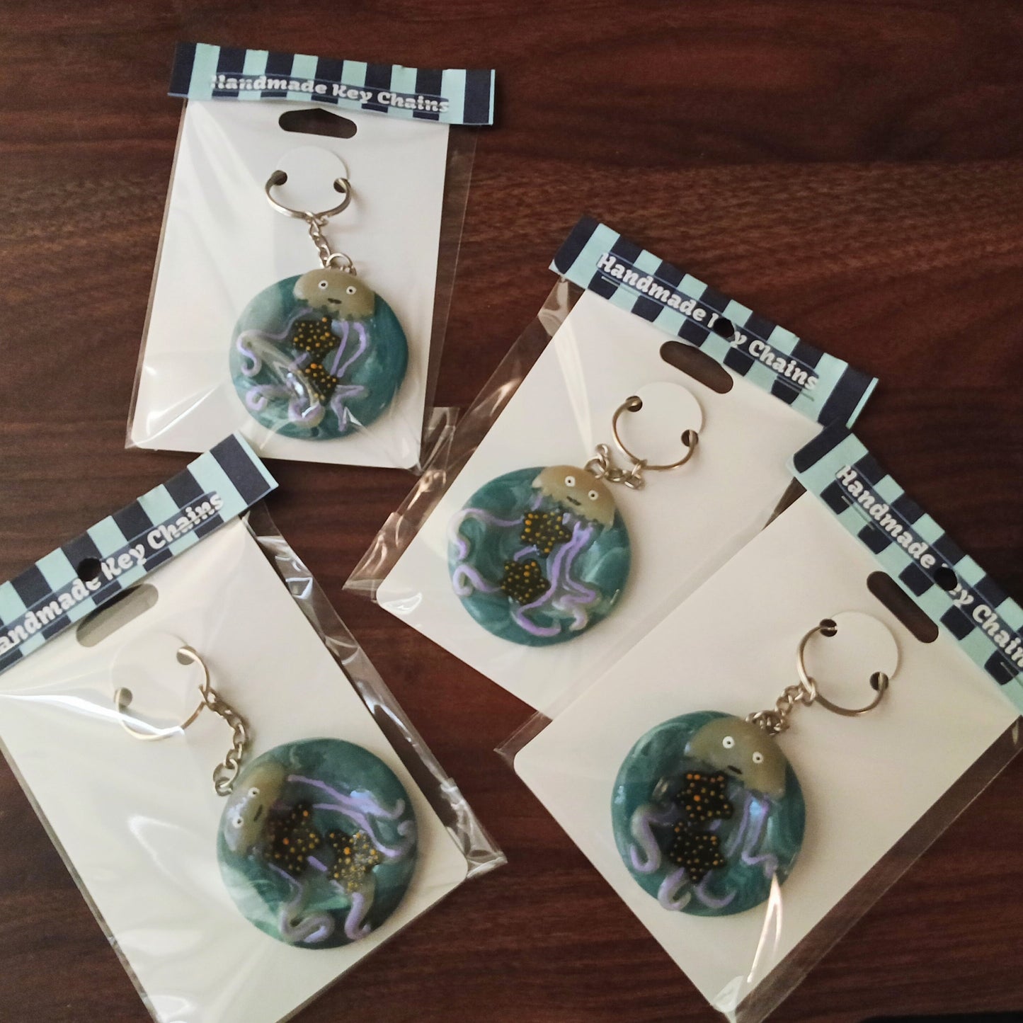Four packages of handmade keychains on a wooden surface