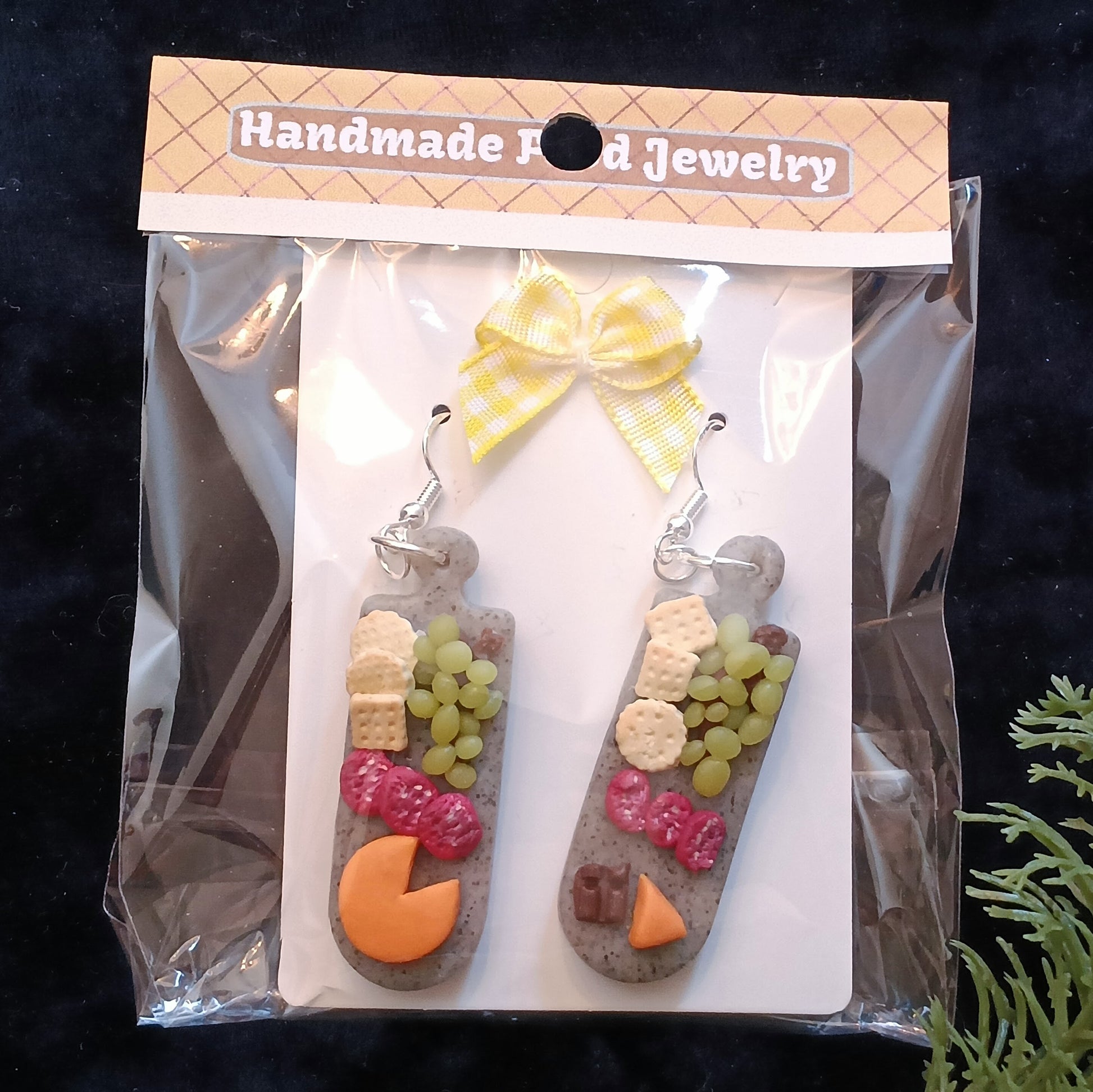 Handmade food-themed earrings in packaging labeled 'Handmade Food Jewelry' on a dark background.