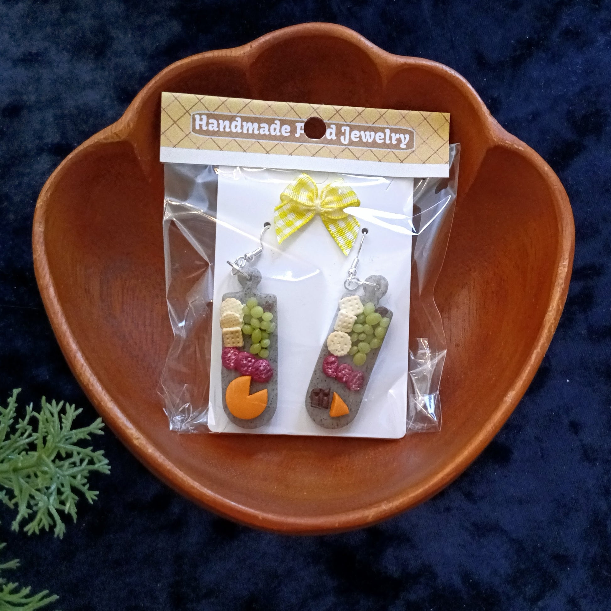 Packaged charcuterie board earrings with a 'Handmade Food Jewelry' label on a dark background.