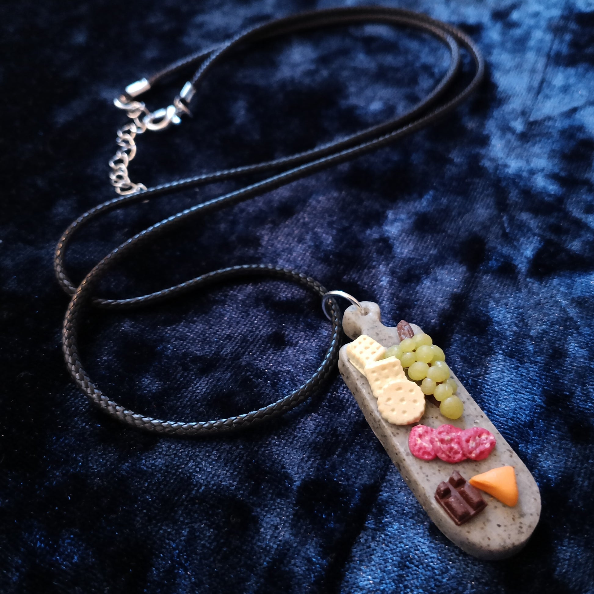 Necklace with a small, detailed pendant on a dark blue textured fabric background