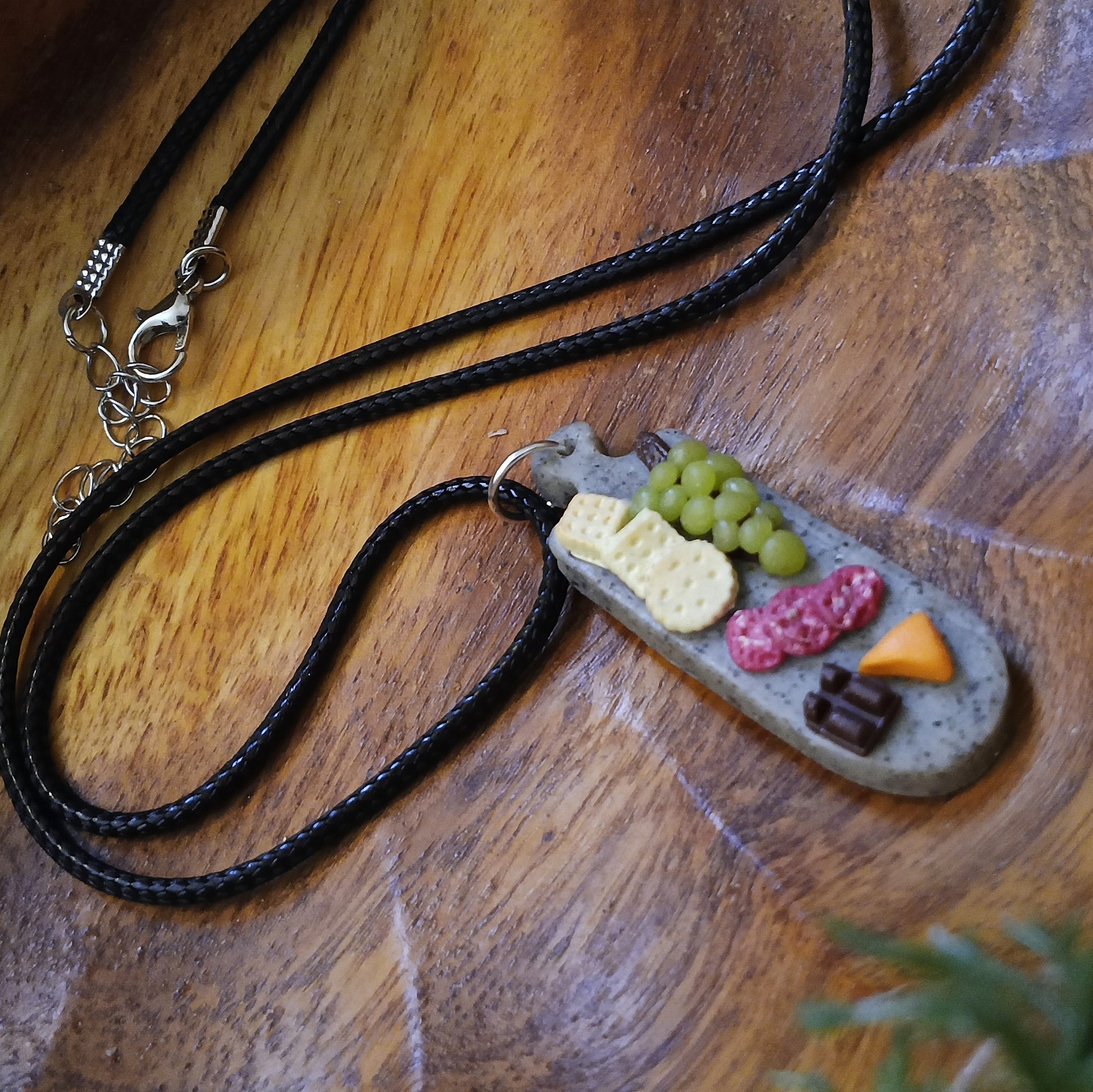 Necklace with a pendant shaped like a plate of food on a wooden surface