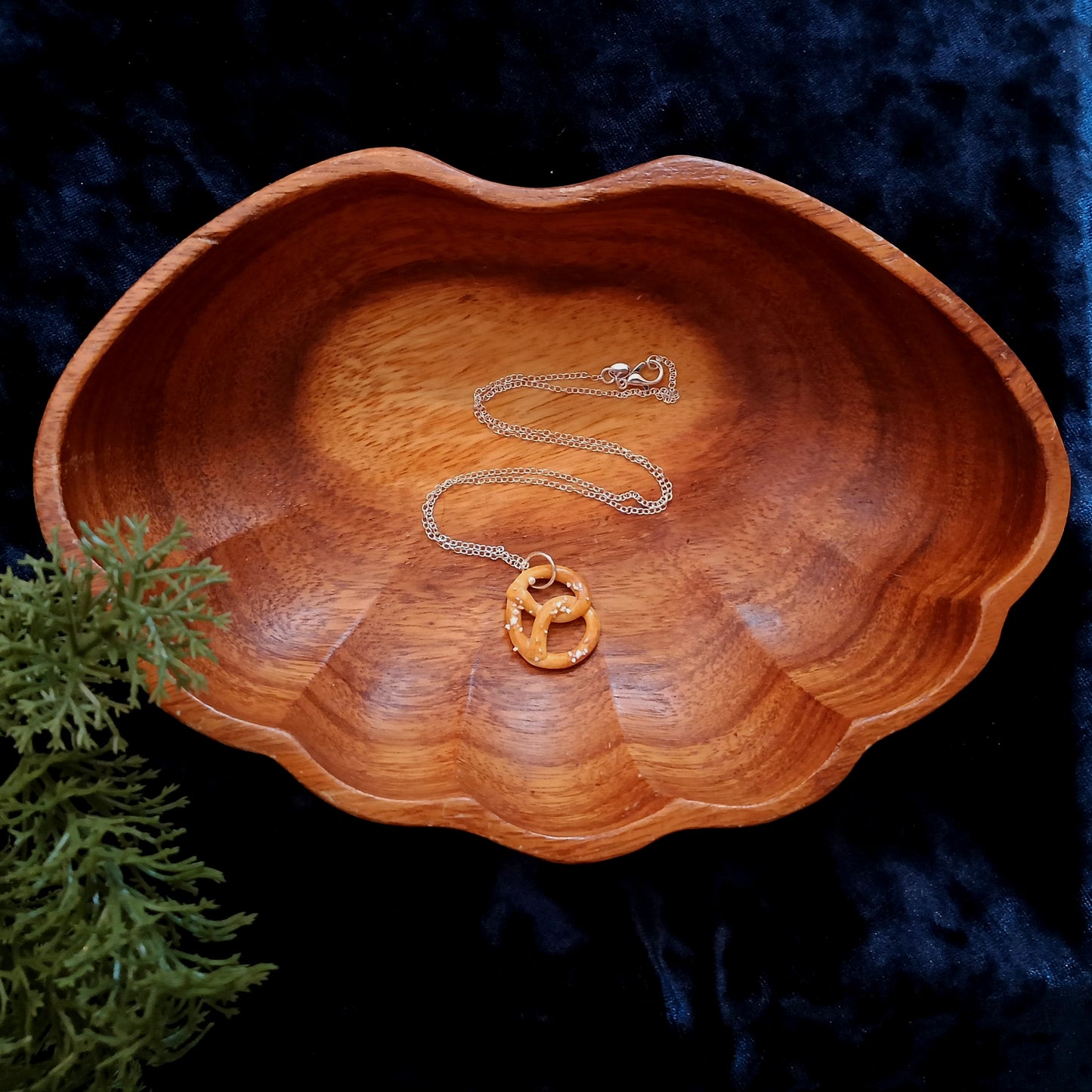 Wooden bowl with a necklace and pendant on a dark blue background