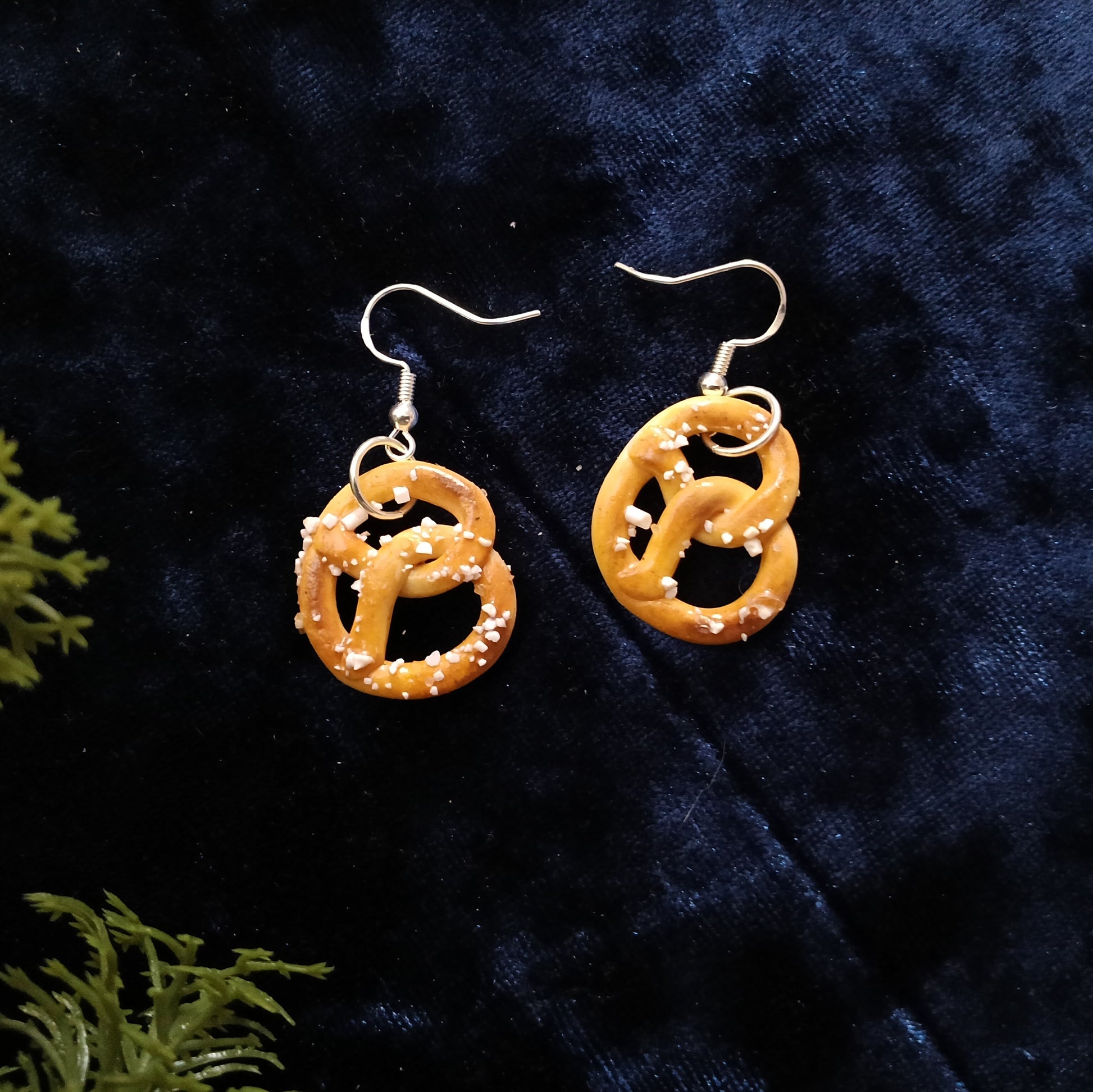 Pretzel-shaped earrings on a dark blue fabric background