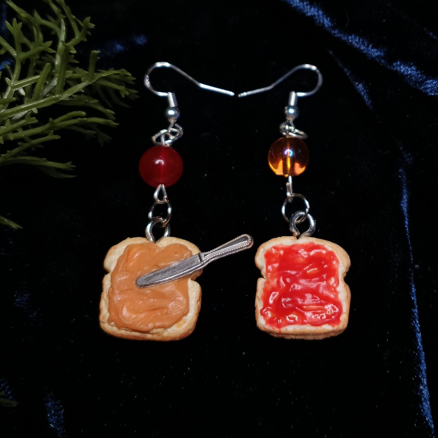 Pair of earrings with peanut butter and jelly design on a dark background