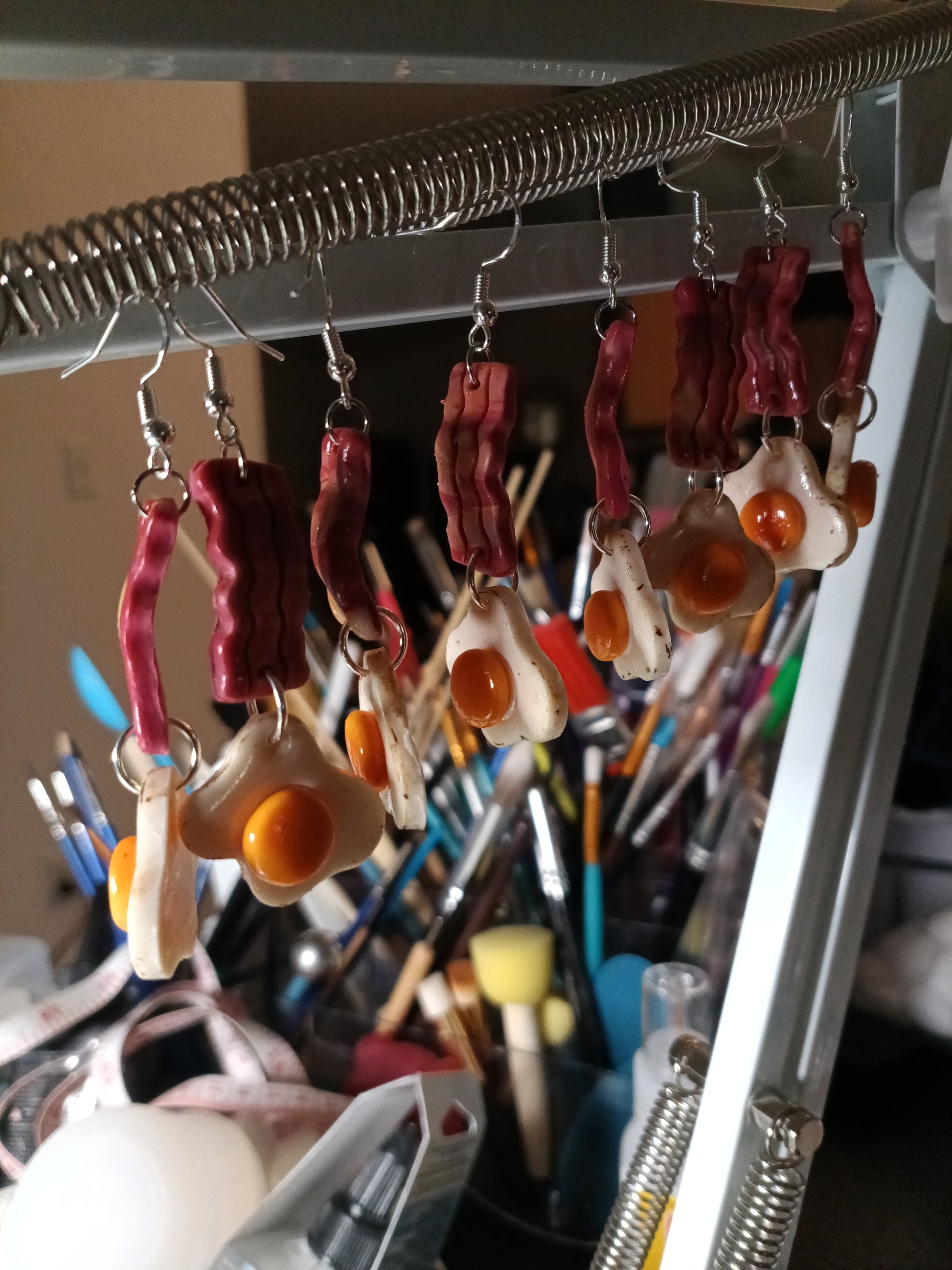 eggs and bacon earrings hanging in art studio 