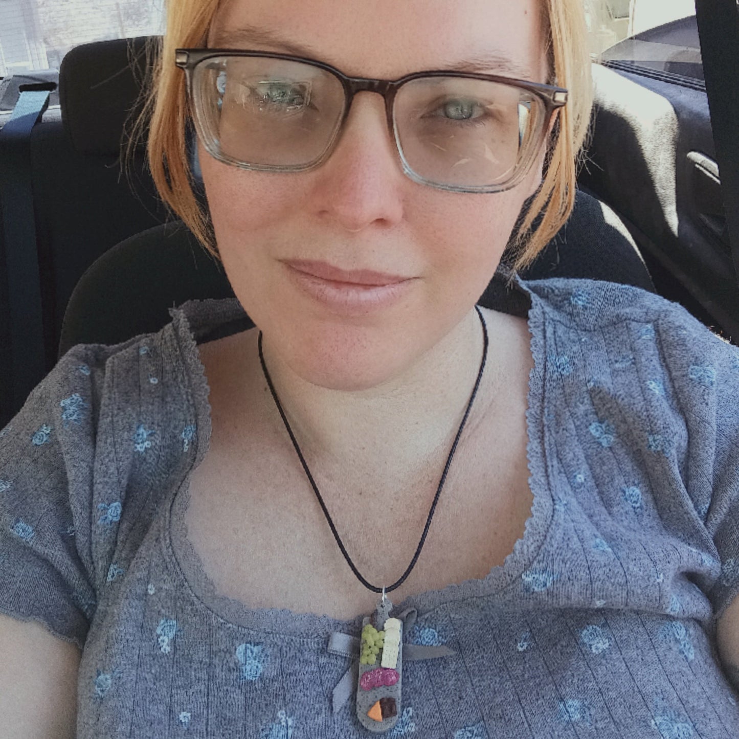 Woman wearing glasses and a necklace inside a vehicle