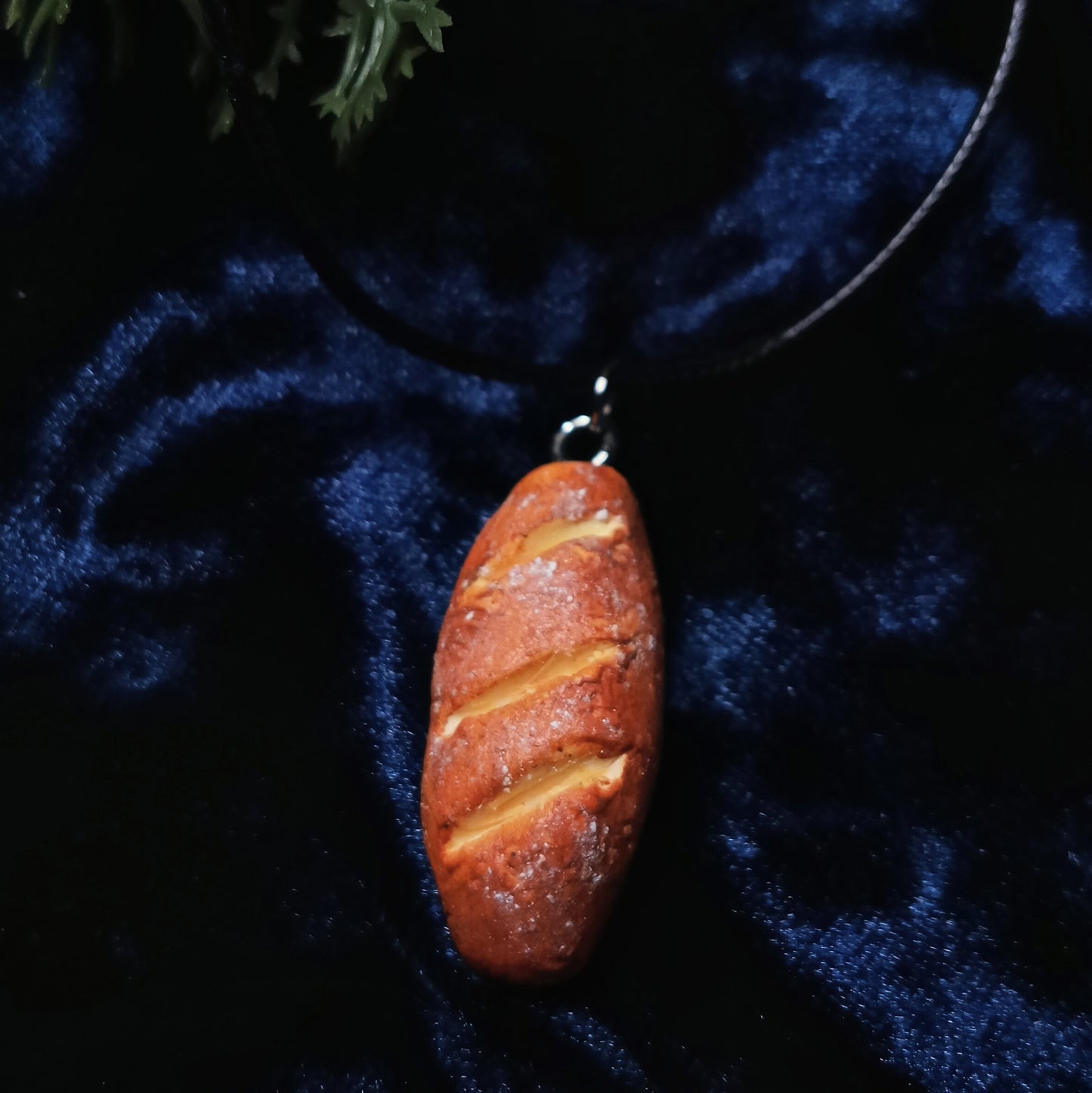 Bread-shaped pendant on a dark blue fabric background