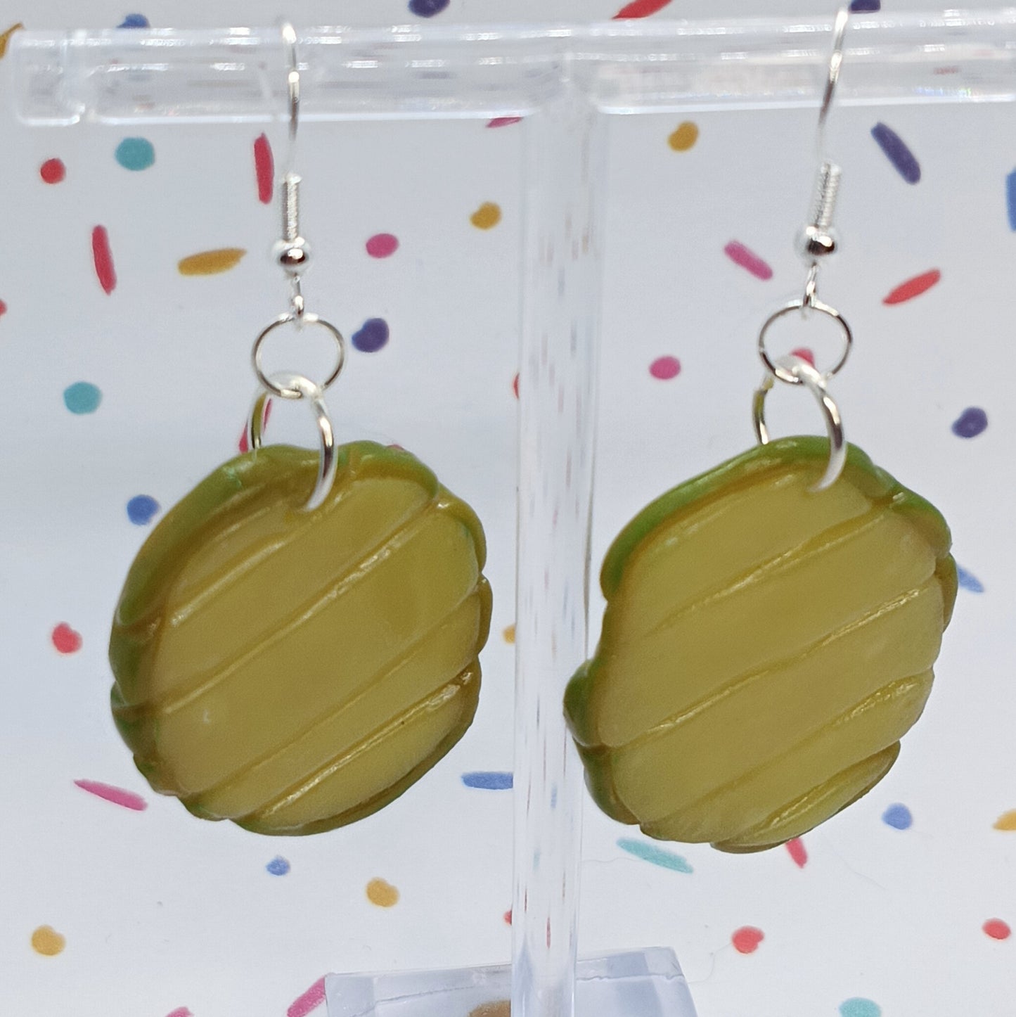 pickle slice earrings on silver hook dangling from clear acrylic stand 