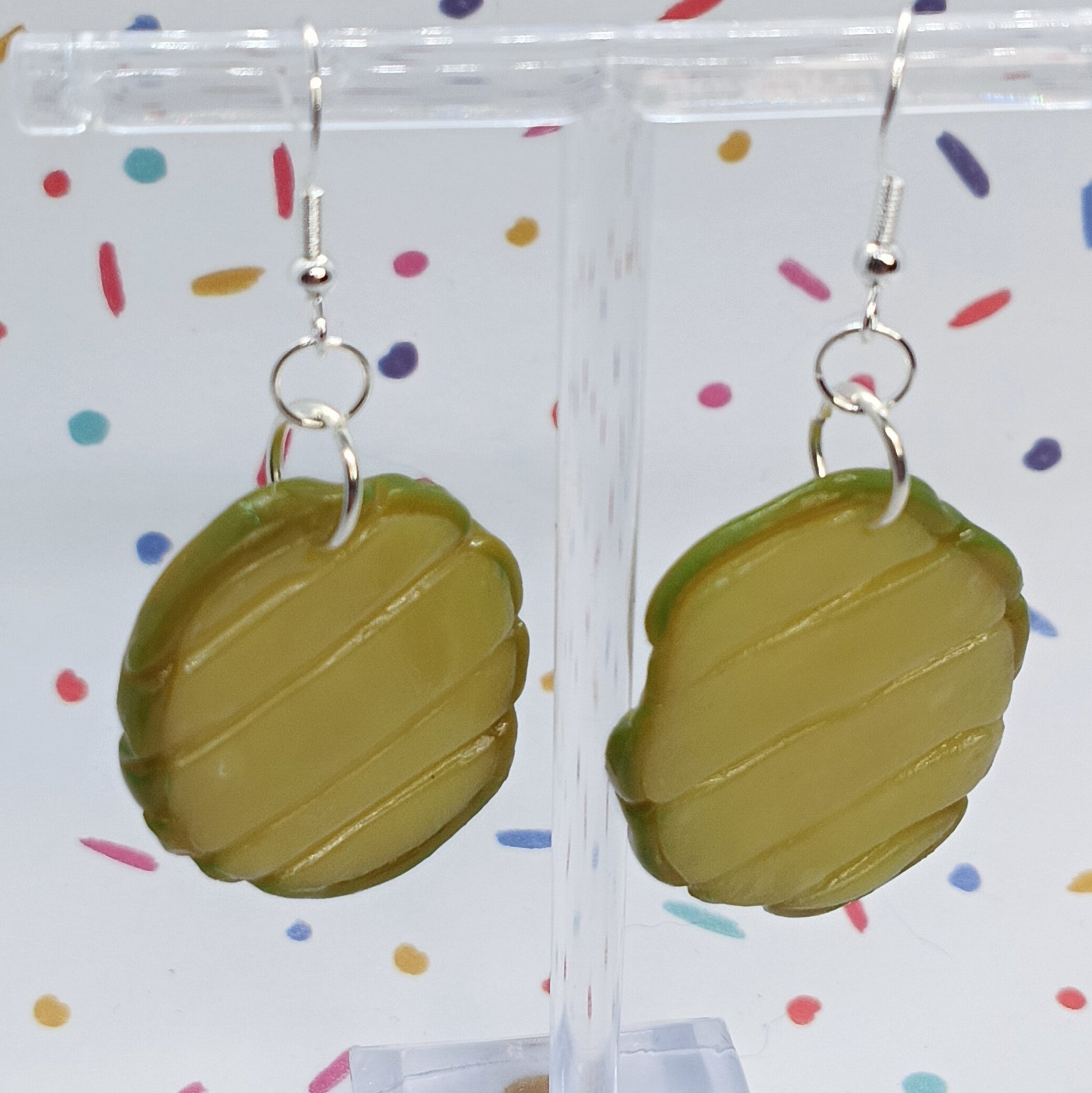pickle slice earrings on silver hook dangling from clear acrylic stand 