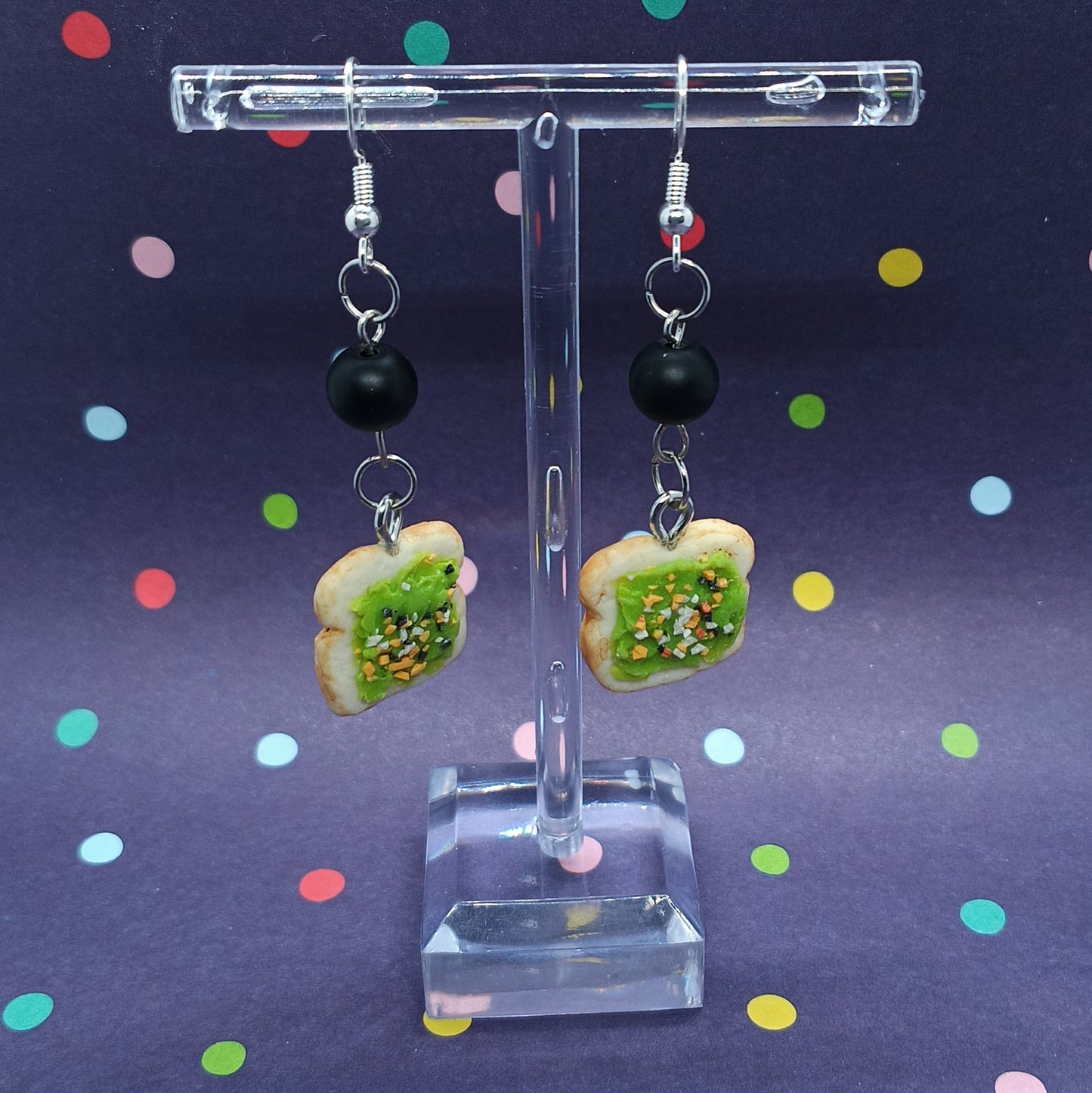 avocado toast dangle earrings on clear stand with polka dot background