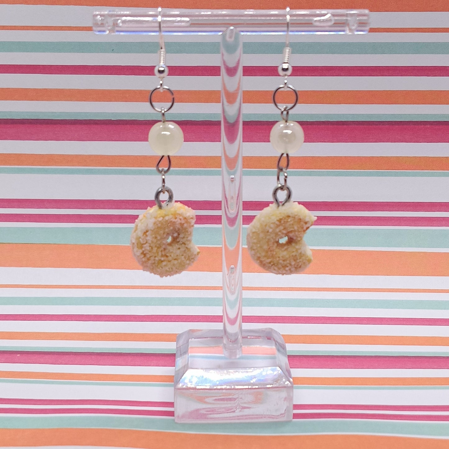Sugar Donuts Earrings on clear stand with striped background