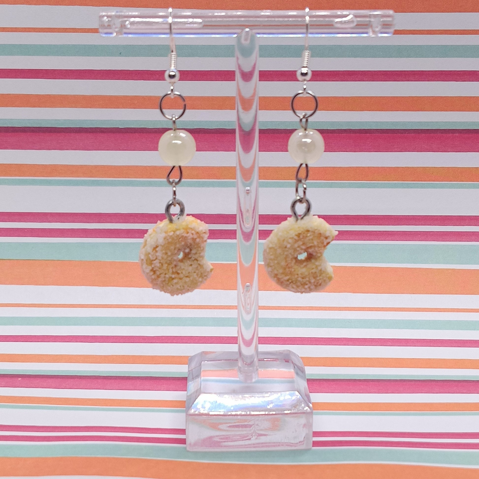 Sugar Donuts Earrings on clear stand with striped background