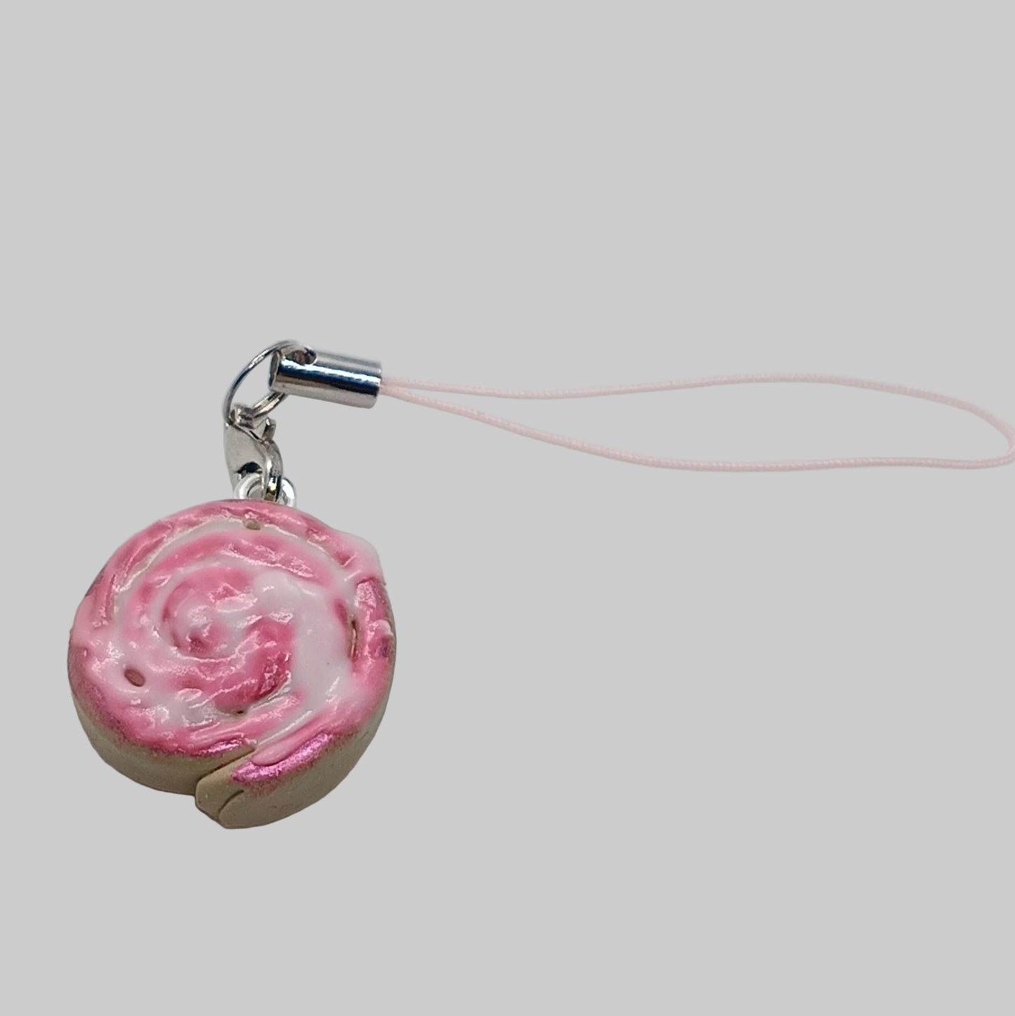 A pink and white swirl charm with a silver clasp and a thin pink cord, shown on a plain white background.