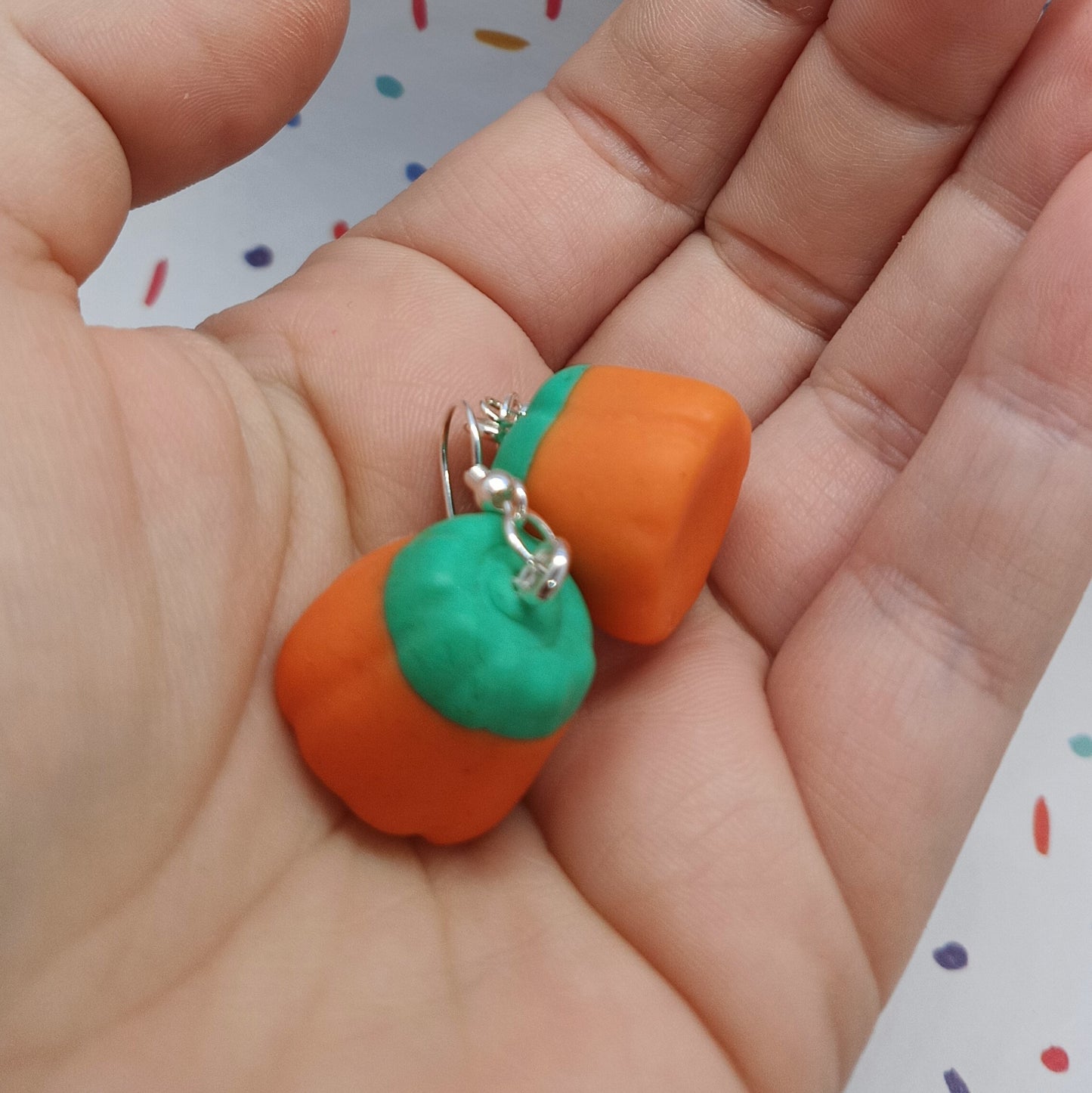 pumpkin candy corn earrings in palm of hand