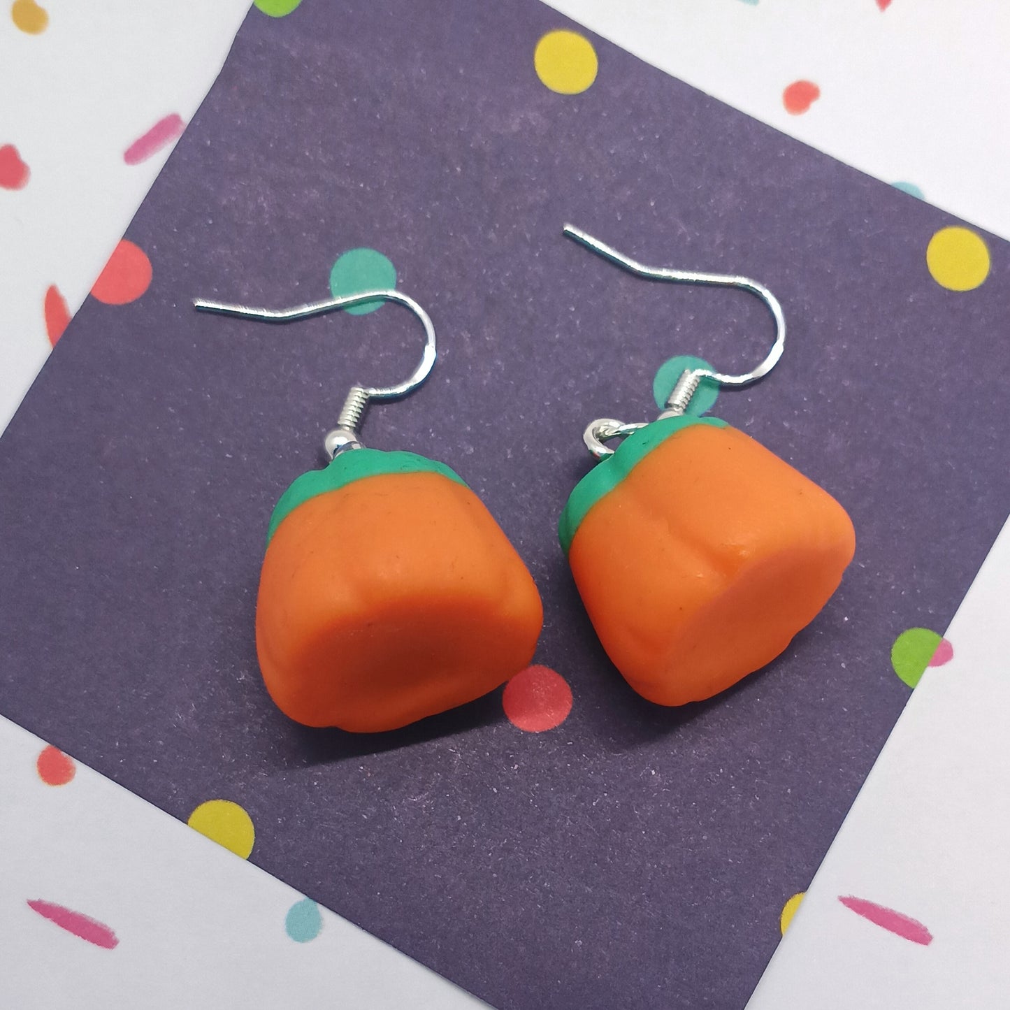 pumpkin candy corn earrings laying on there sides 