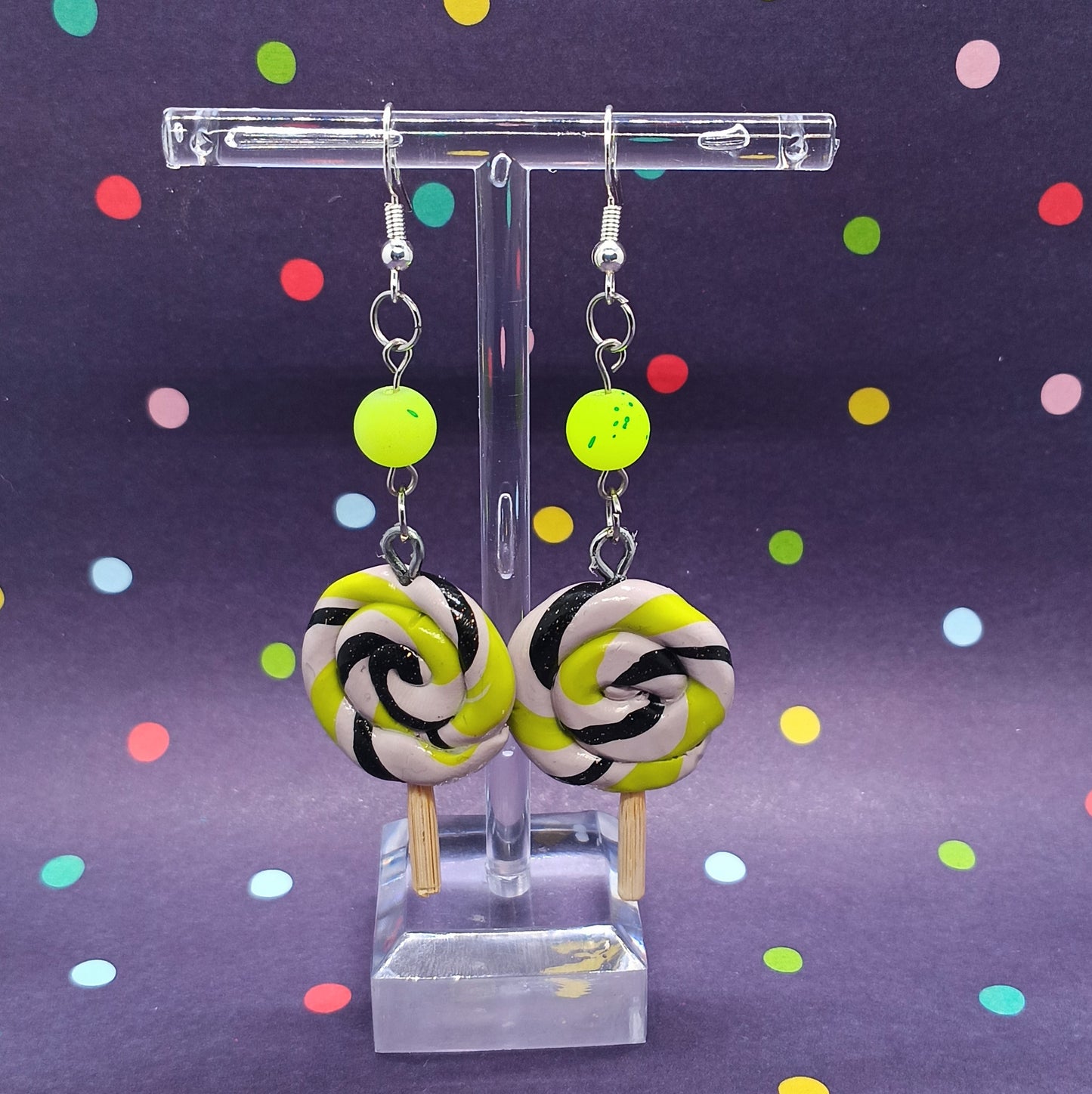 Lollipop swirl earrings on clear stand and polka dot background 